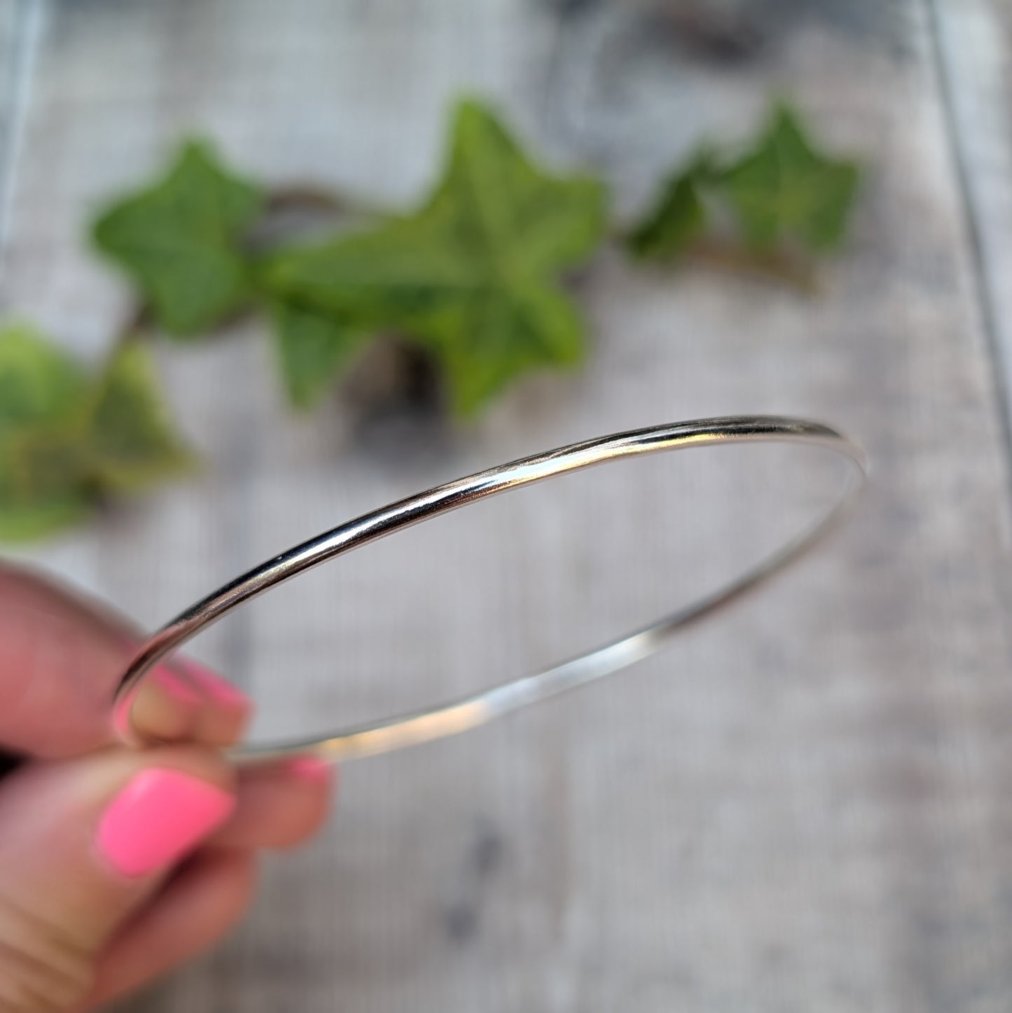 Close up side view of a Silver 2mm Smooth Round Bangle handmade from recycled Sterling Silver wire, showing the smooth rounded surface.