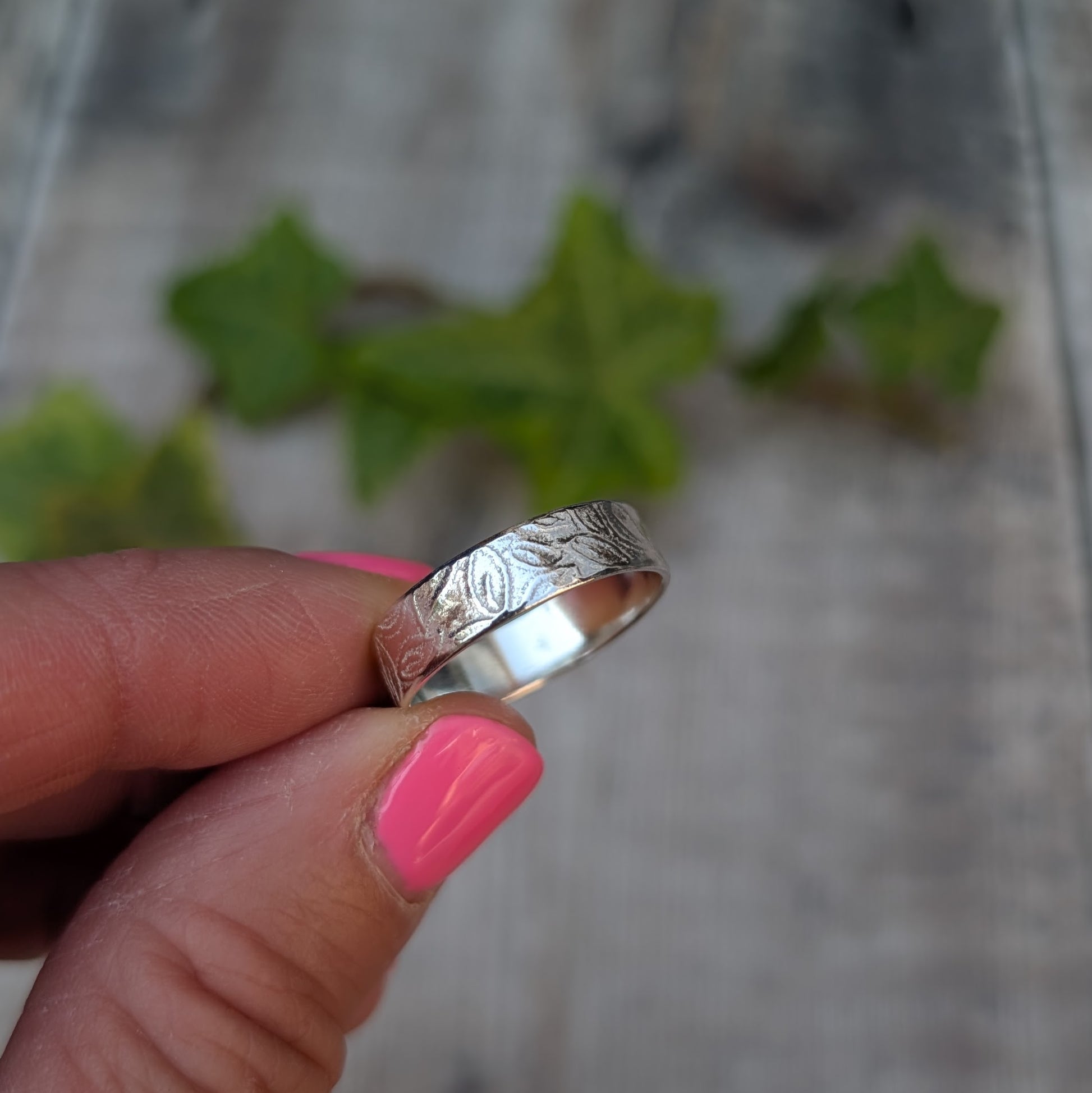 Silver 5mm Leaf Patterned Ring handmade from recycled Sterling Silver, held between fingers showing the hand stamped leaf design.