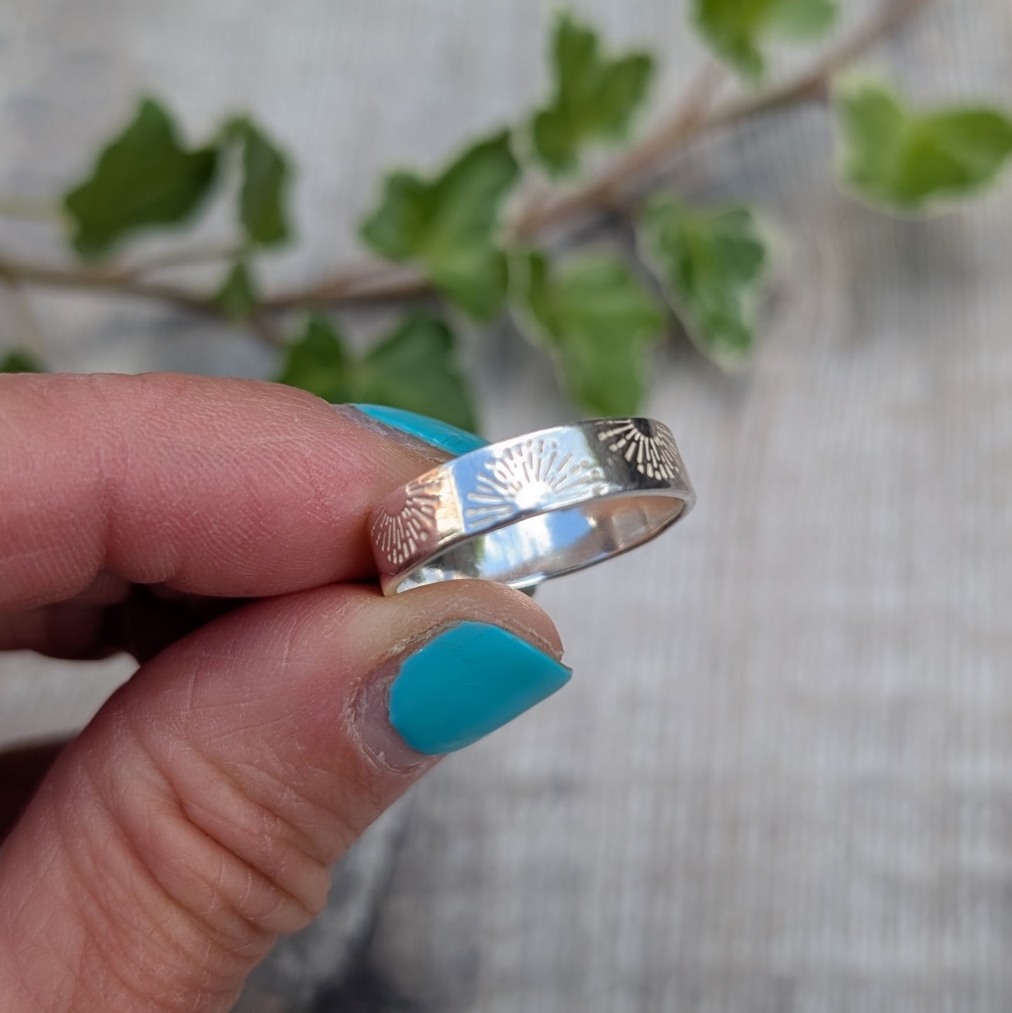 Silver 5mm Sunrise Ring handmade from recycled Sterling Silver with a hand stamped sunrise pattern, shown held between fingers from a different angle.