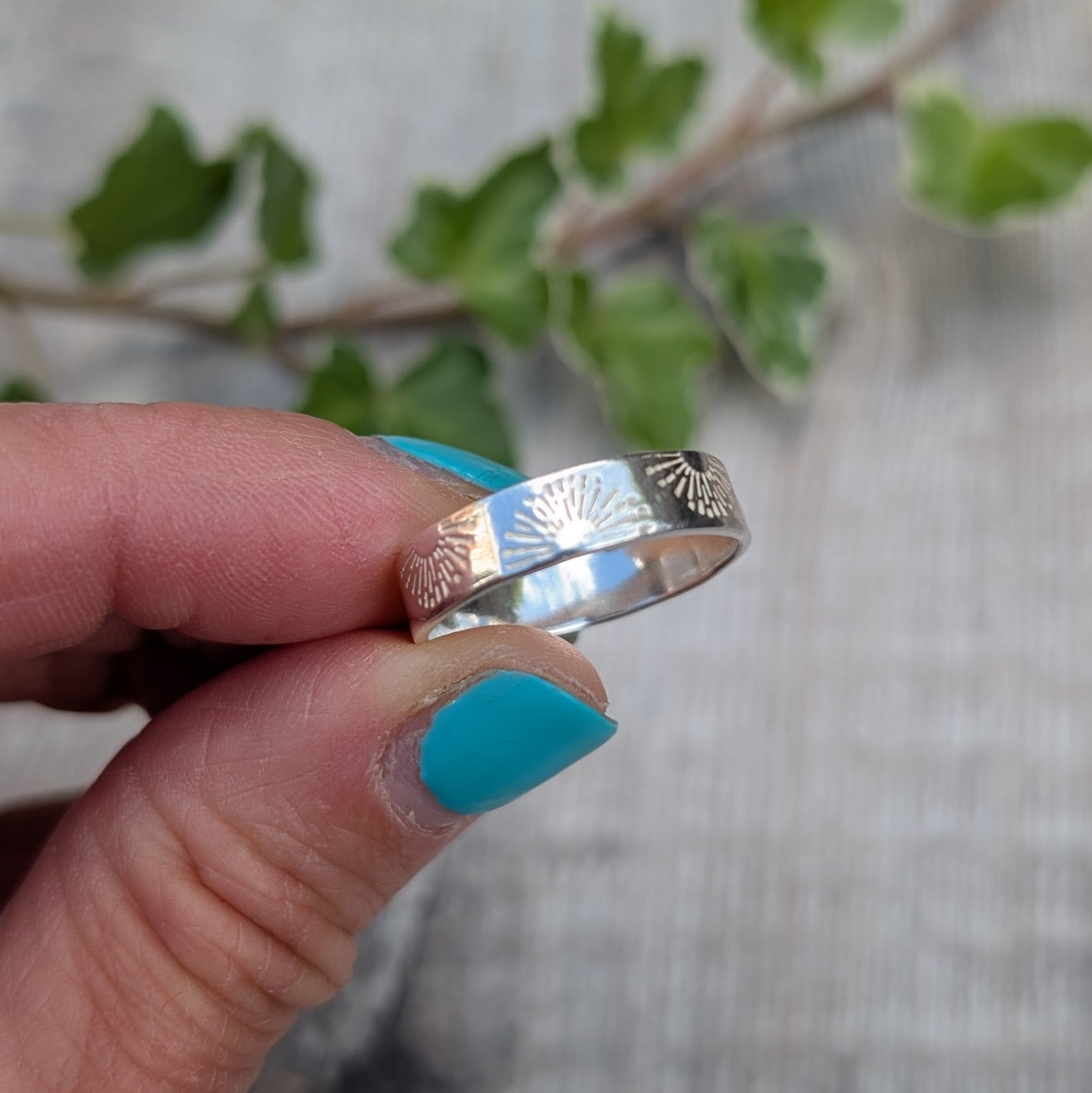 Silver 5mm Sunrise Ring handmade from recycled Sterling Silver with a hand stamped sunrise pattern, shown held between fingers from a different angle.