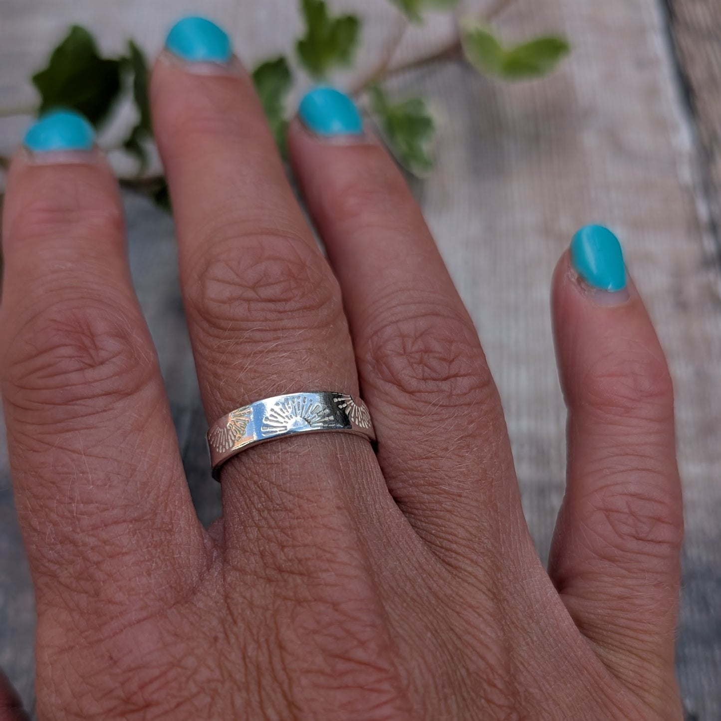 Silver 5mm Sunrise Ring handmade from recycled Sterling Silver with a hand stamped sunrise pattern, shown being worn on a hand.