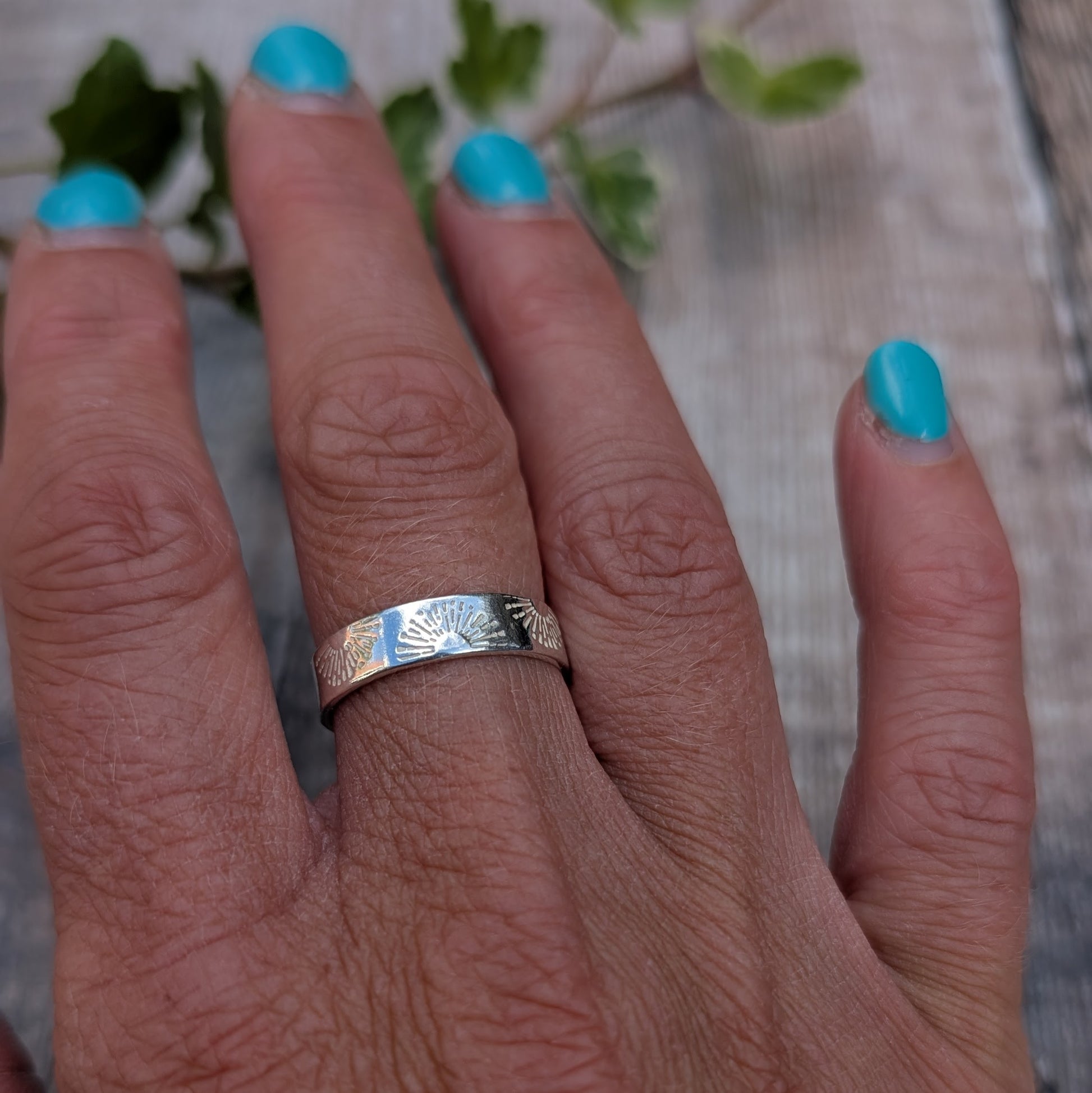 Silver 5mm Sunrise Ring handmade from recycled Sterling Silver with a hand stamped sunrise pattern, shown being worn on a hand.