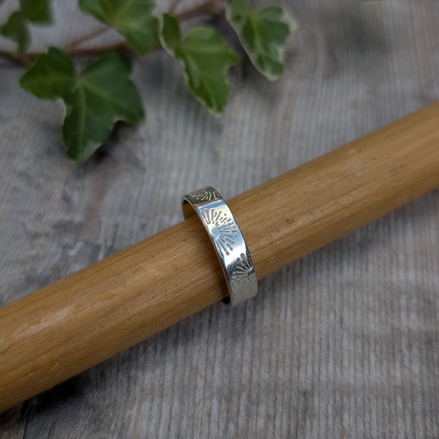 Silver 5mm Sunrise Ring handmade from recycled Sterling Silver with a hand stamped sunrise pattern, displayed on a wooden ring mandrel.