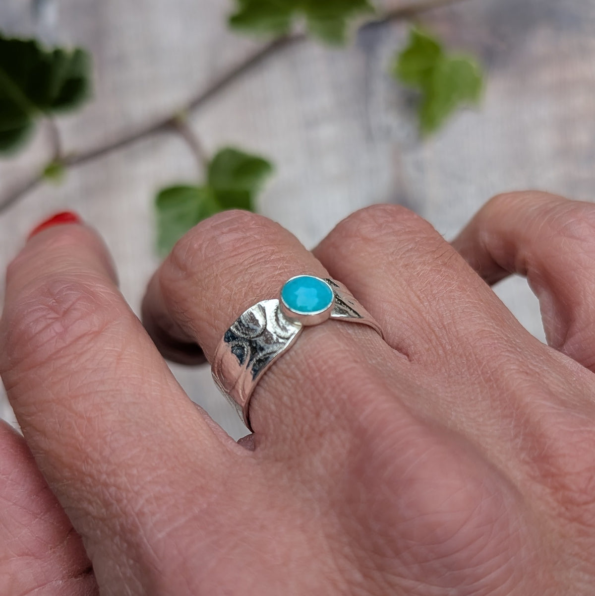 Silver oval patterned Amazonite wide band ring worn on a hand, showing the bright blue oval Amazonite stone and textured silver band.