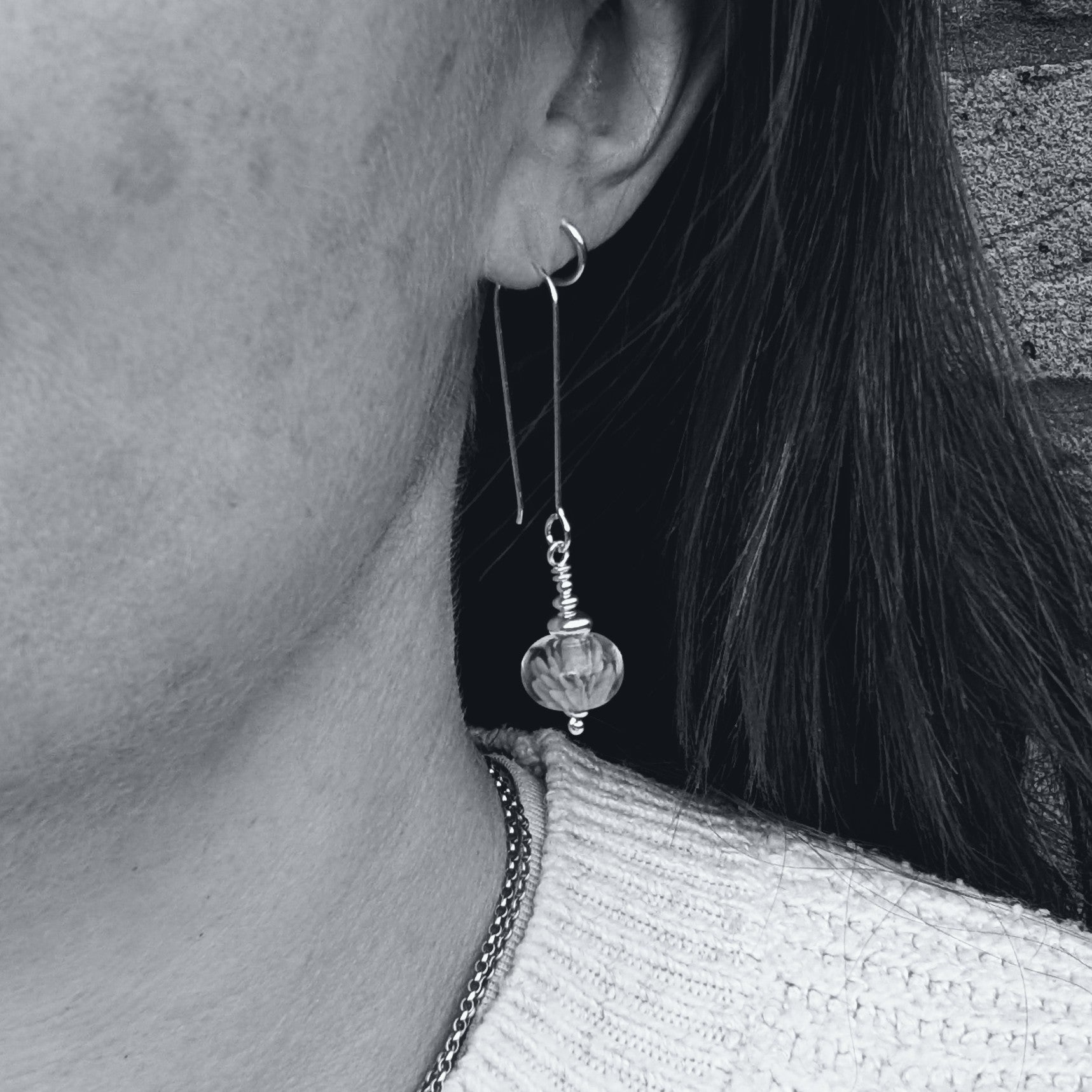 Silver Blue Lampwork Glass Earrings worn in the ear, showing the length of the silver hooks and the round glass bead drop in profile.