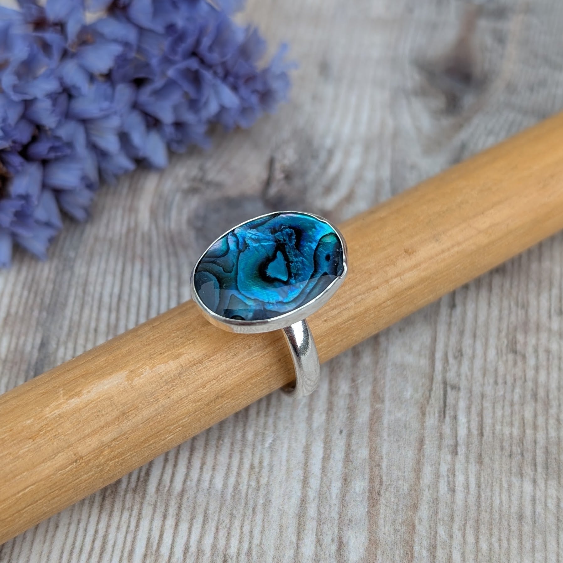Silver Blue Paua Shell Ring displayed on a wooden ring mandrel showing the handmade recycled Sterling Silver band.