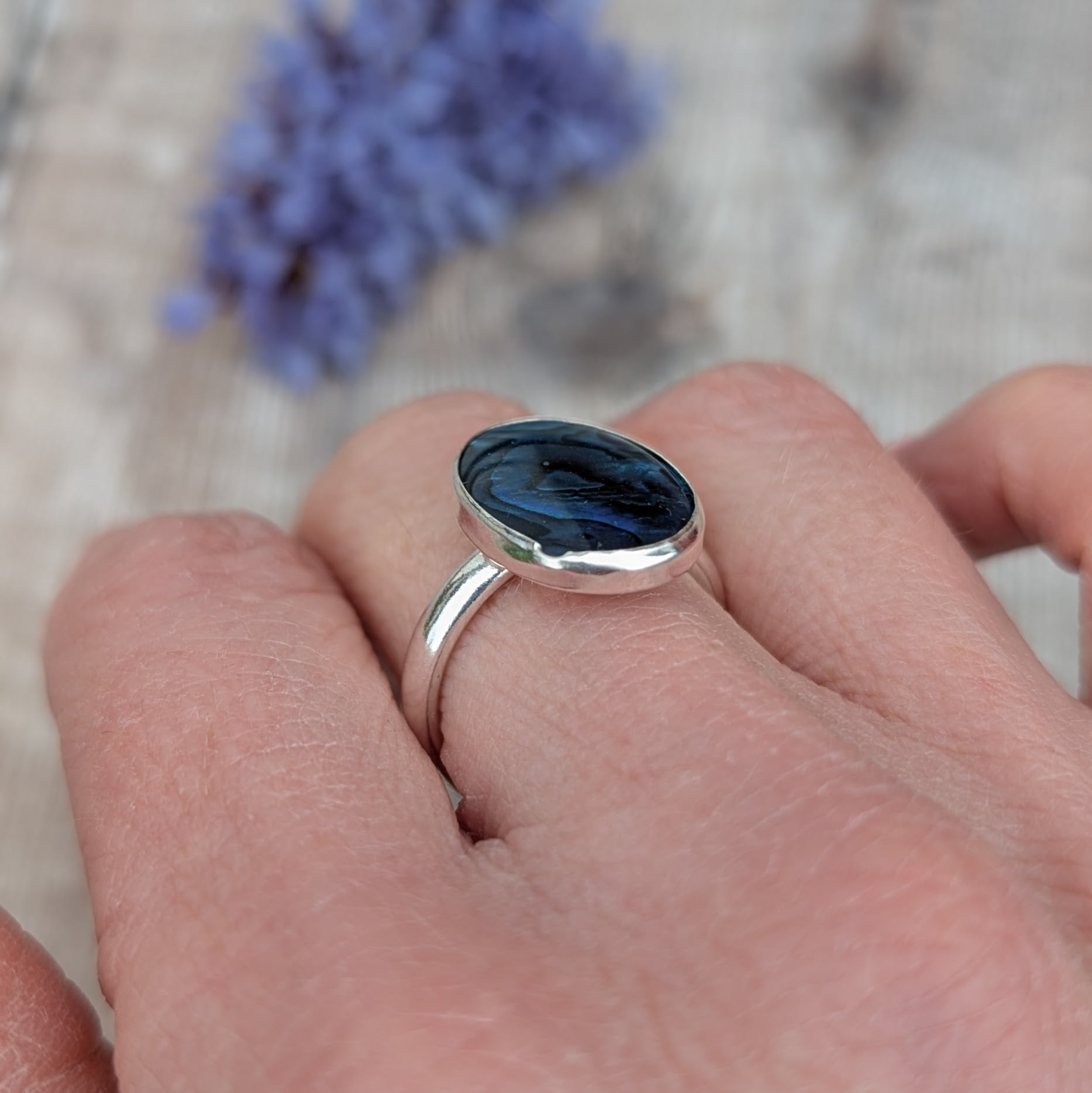 Side view of the Silver Blue Paua Shell Ring worn on a hand showing the depth of the Paua Shell setting in recycled Sterling Silver.