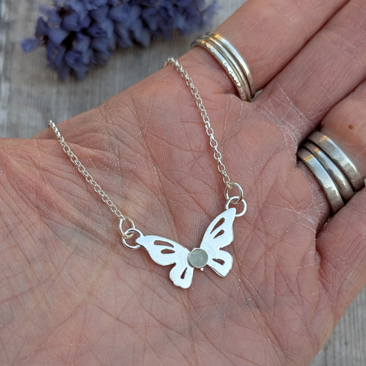 Silver Butterfly Necklace with Aquamarine held in a hand showing the scale and fine detail of the butterfly shape