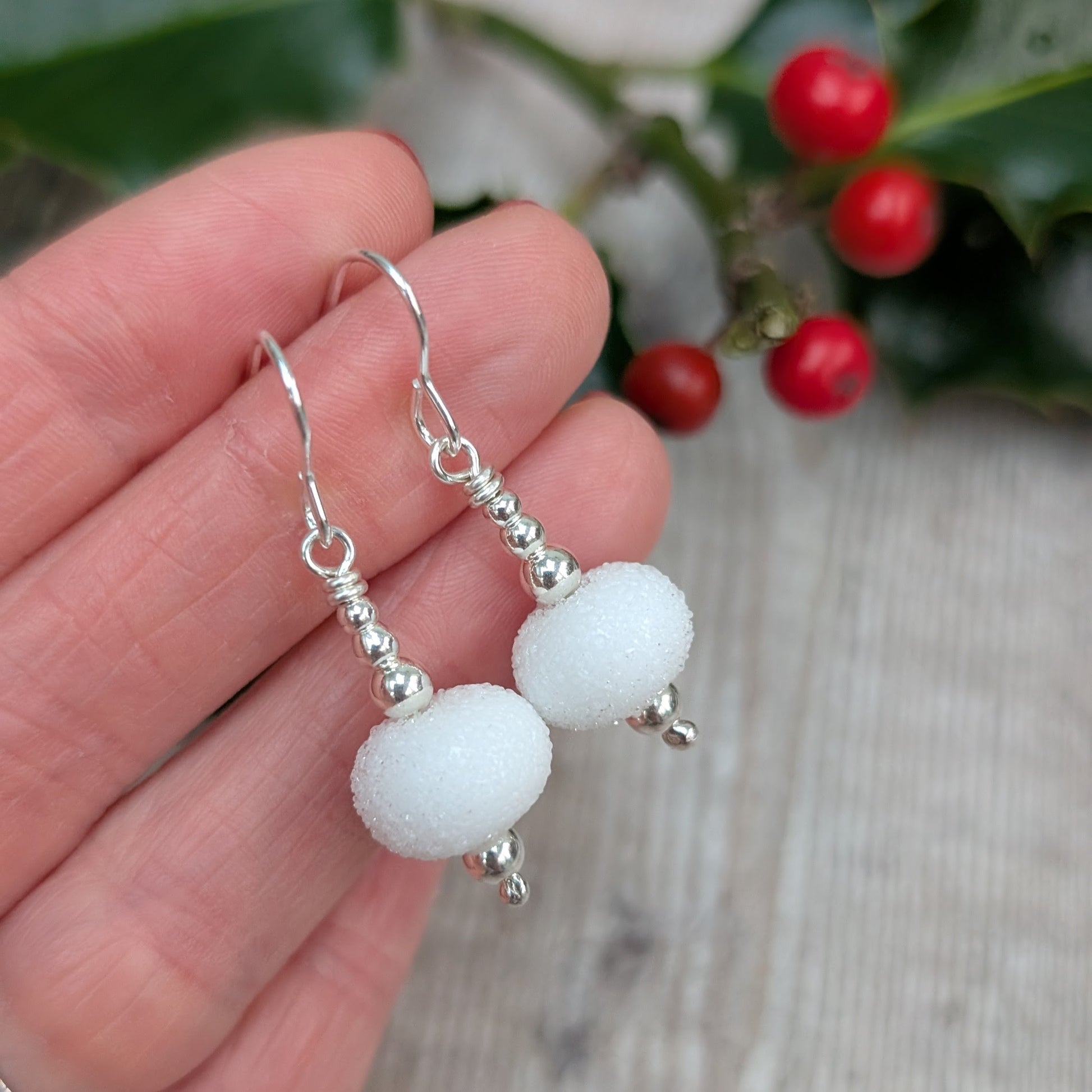 Close-up of the Silver Christmas Snowball Lampwork Glass Earrings against a natural background, showing the snowy matte glass beads paired with shiny silver bead caps.