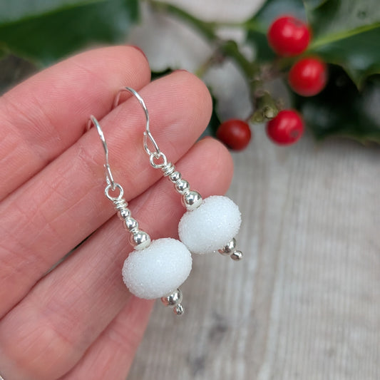 Close-up of the Silver Christmas Snowball Lampwork Glass Earrings against a natural background, showing the snowy matte glass beads paired with shiny silver bead caps.