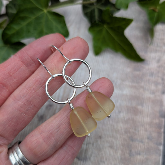 Hand holding Silver Circle Earrings with Yellow Sea Glass Beads made from recycled Sterling Silver.