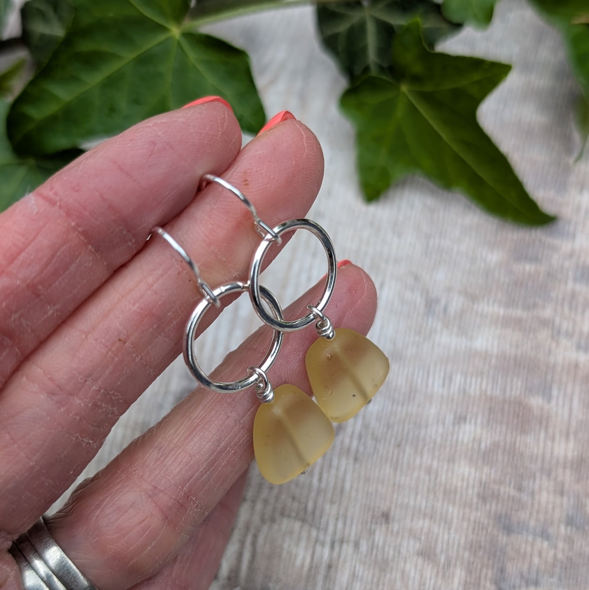 Detailed view of Silver Circle Earrings with Yellow Sea Glass Beads hanging from silver hooks.