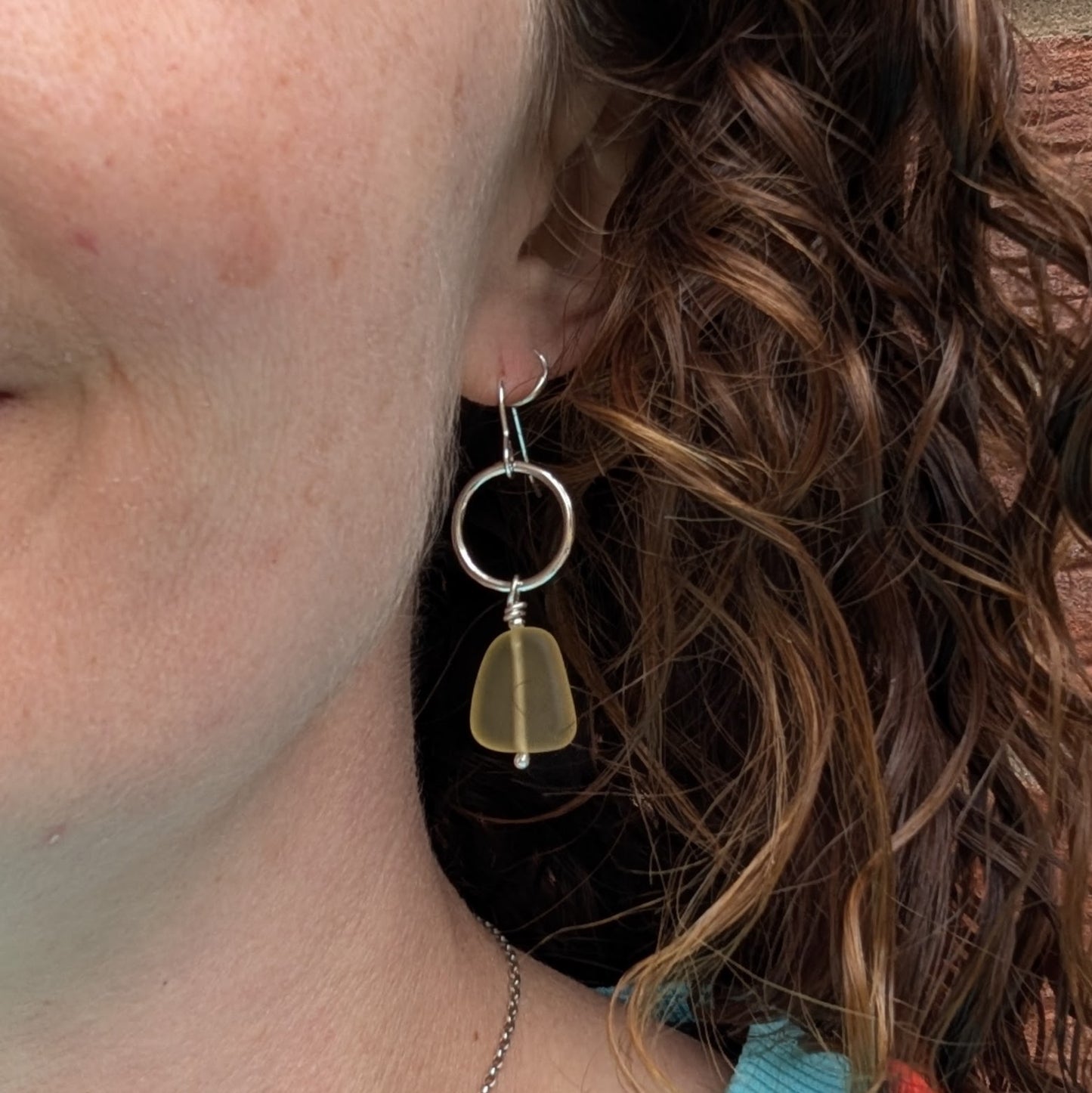 Handmade Silver Circle Earrings with Yellow Sea Glass Beads shown worn in the ear.