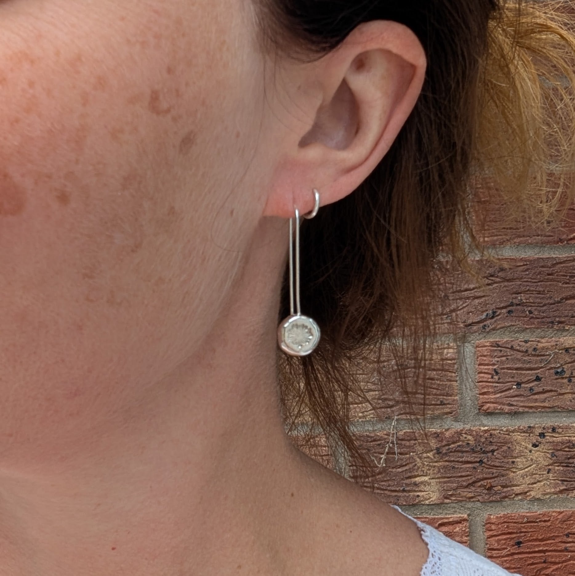 silver daisy pebble long earrings being worn, showing the length and size of the handmade recycled Sterling Silver earrings.