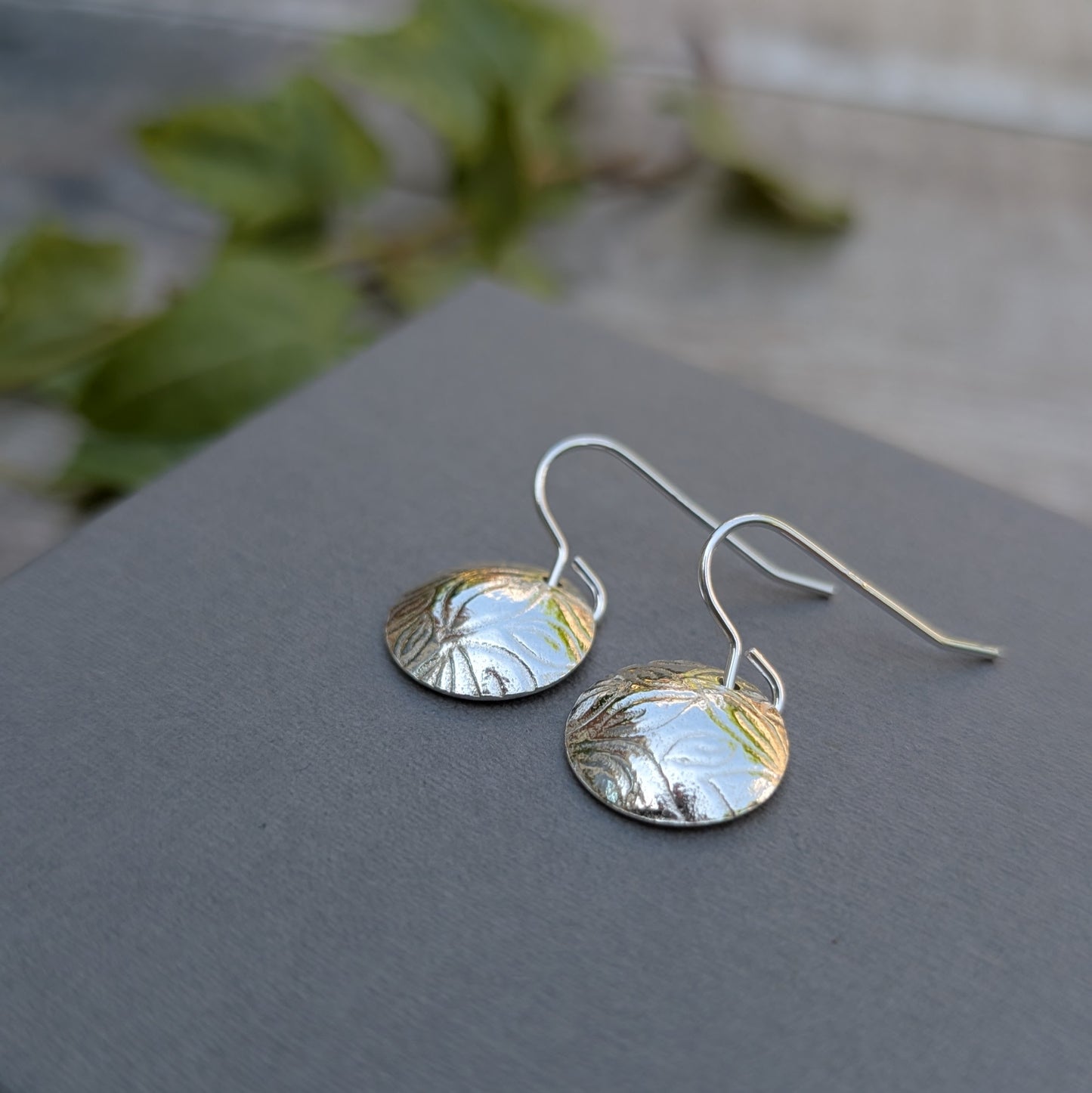 Side view of Silver Dome Disc Earrings with Leaf Pattern showing the domed shape and hook wires.