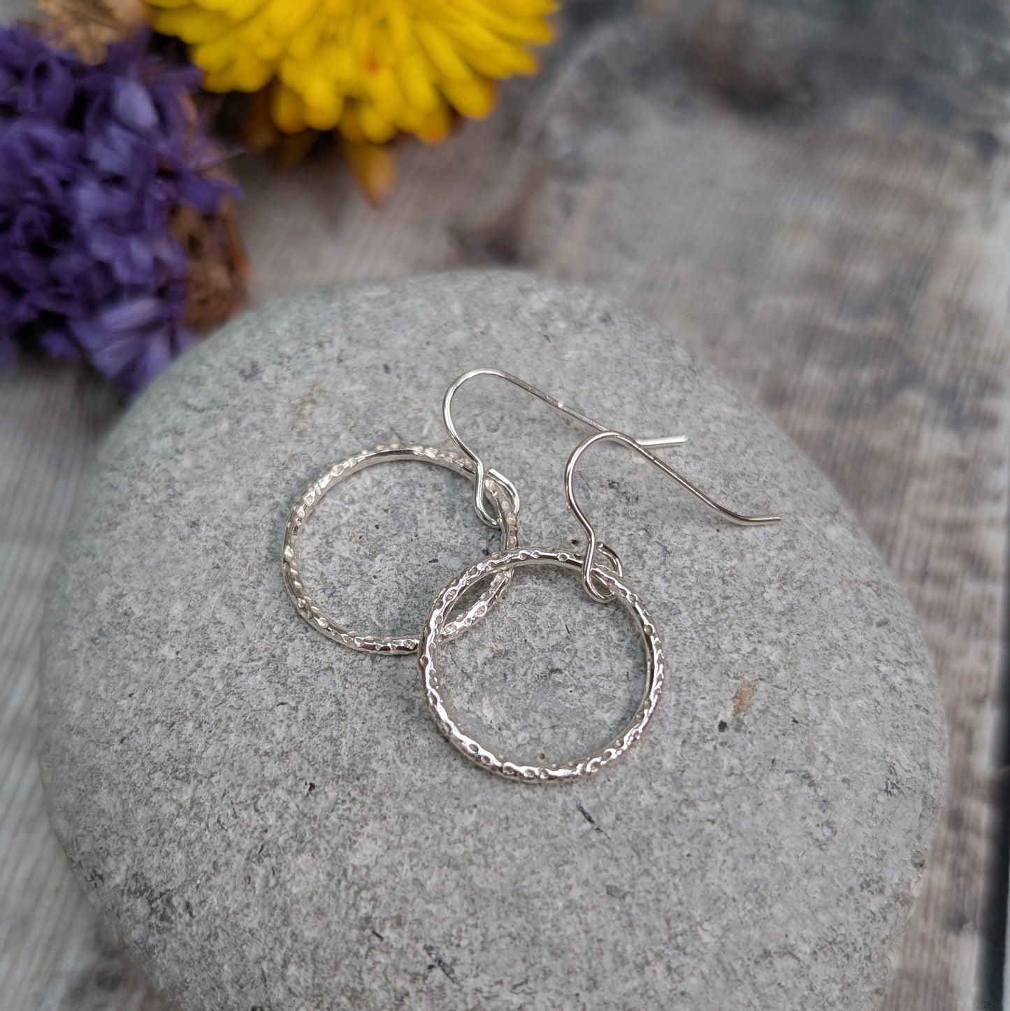 Close-up of Silver Dot Textured Circle Earrings on a stone, showing the reflective dotted surface and delicate silver finish.