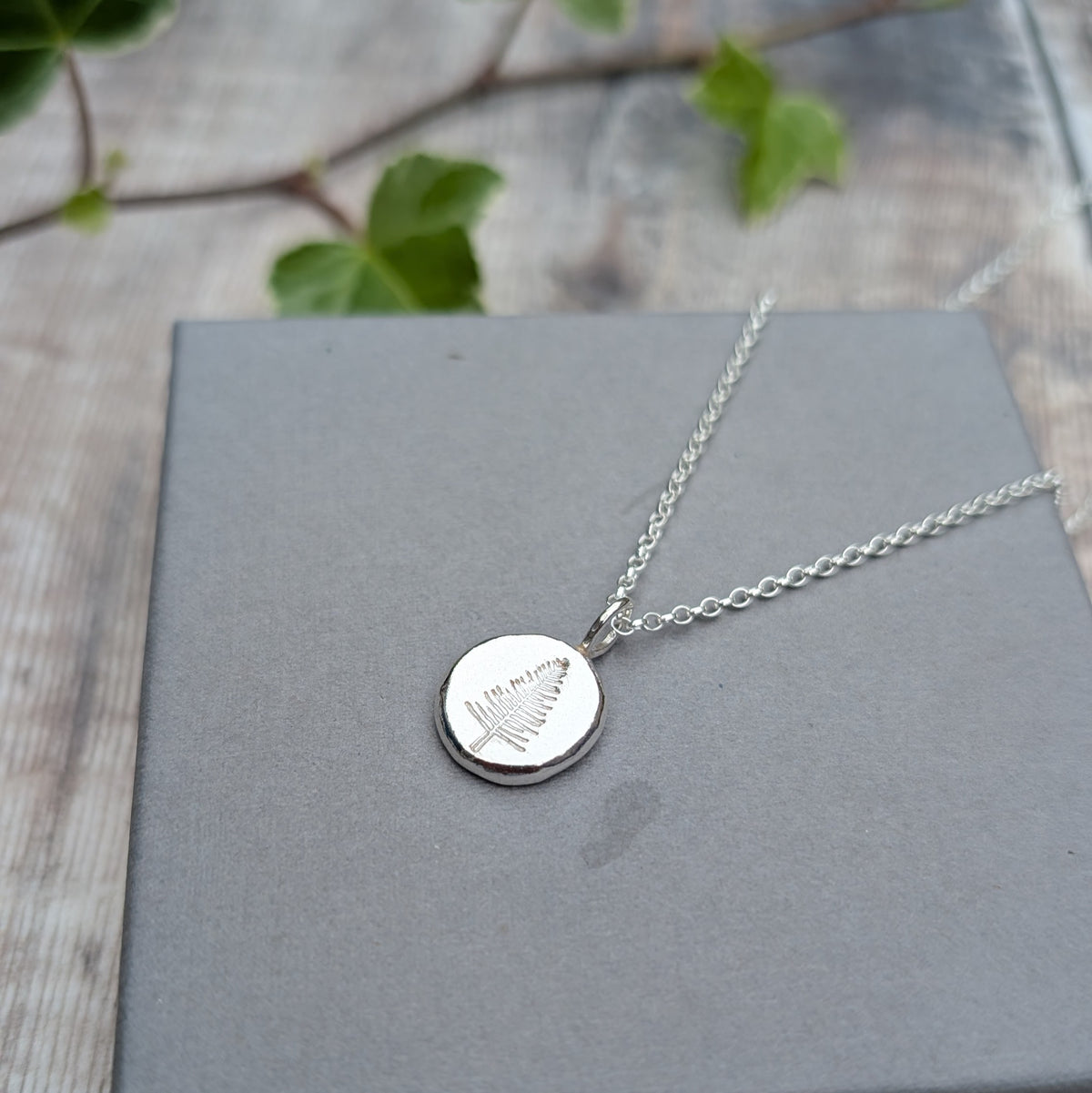 Silver evergreen tree necklace handmade from recycled Sterling Silver, with a stamped tree design on a round pebble pendant.