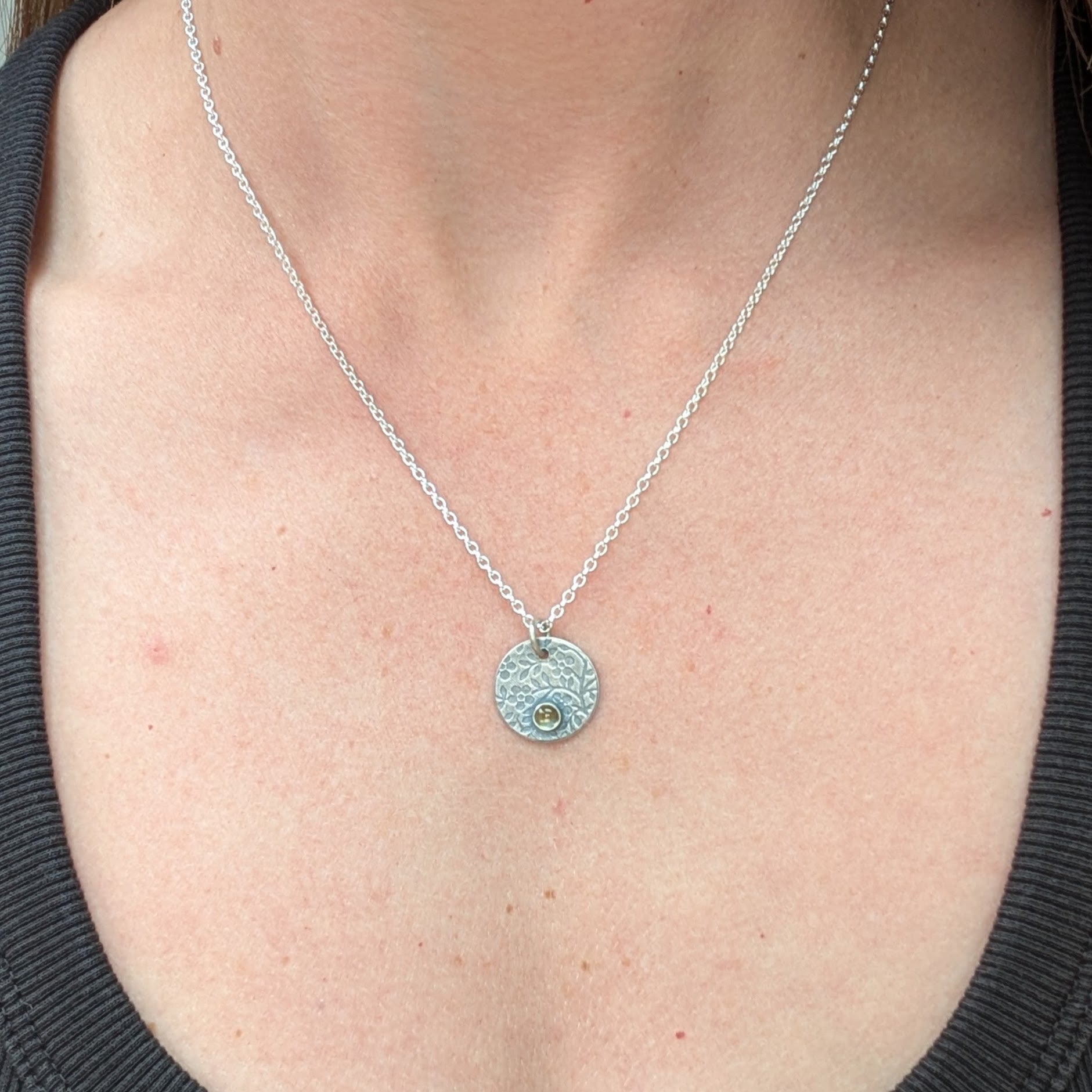 Silver flower disc necklace with citrine pendant being worn, showing the round pendant on a fine silver chain.