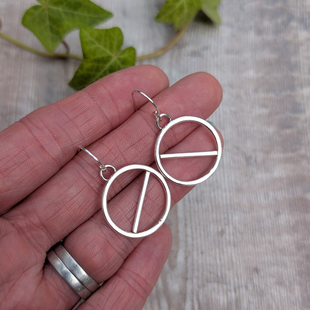 Silver geometric circle earrings handmade from recycled Sterling Silver, shown held in a hand to give an idea of their size.