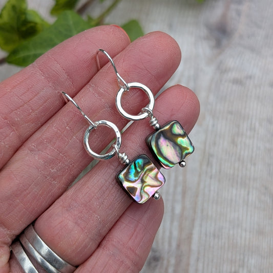 Hand holding Silver Hammered Circle Earrings with Abalone Shell Beads to show size and detail