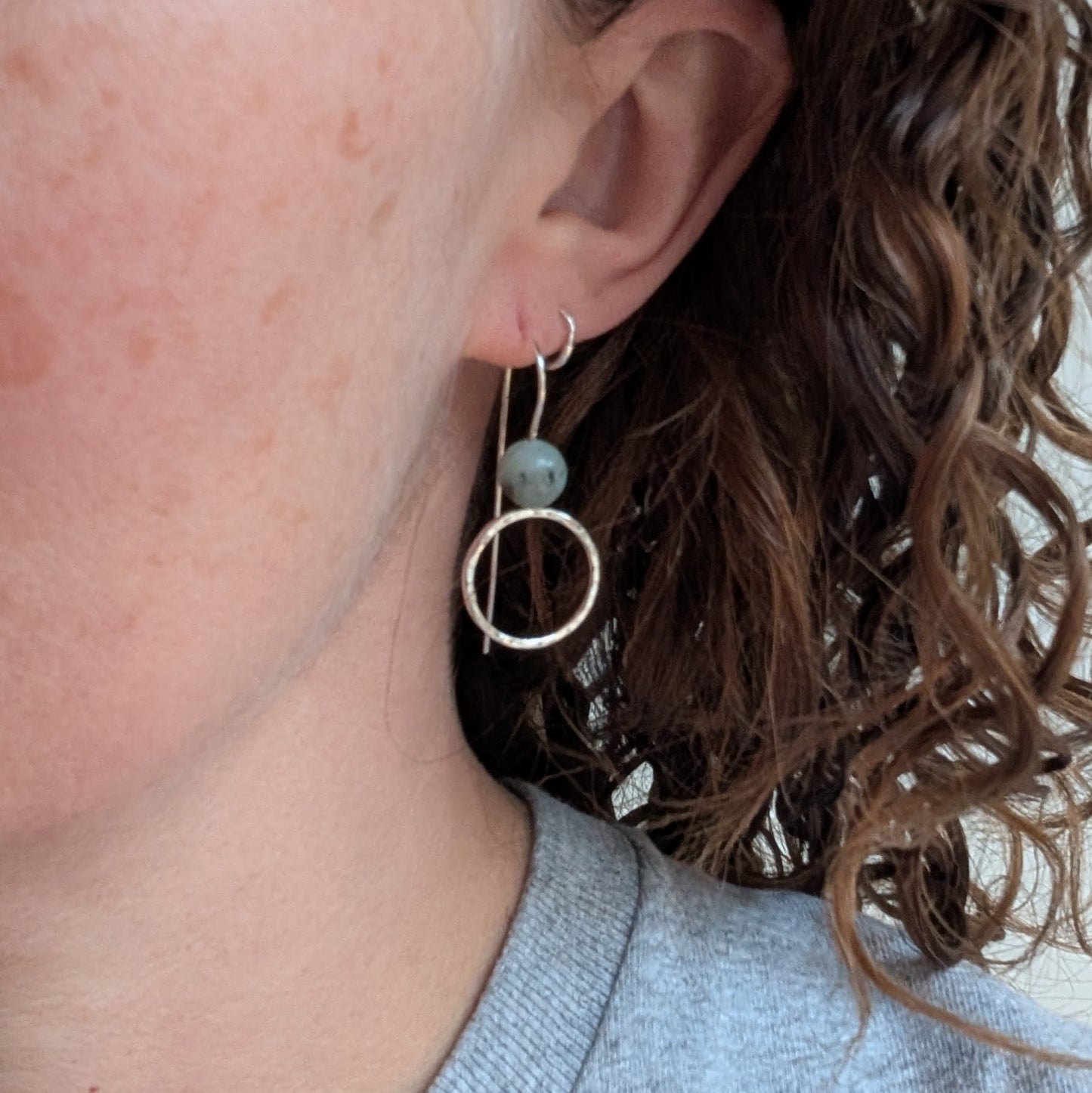 Silver Hammered Circle Earrings with Kiwi Jasper worn on an ear, showing their light, elegant drop design.