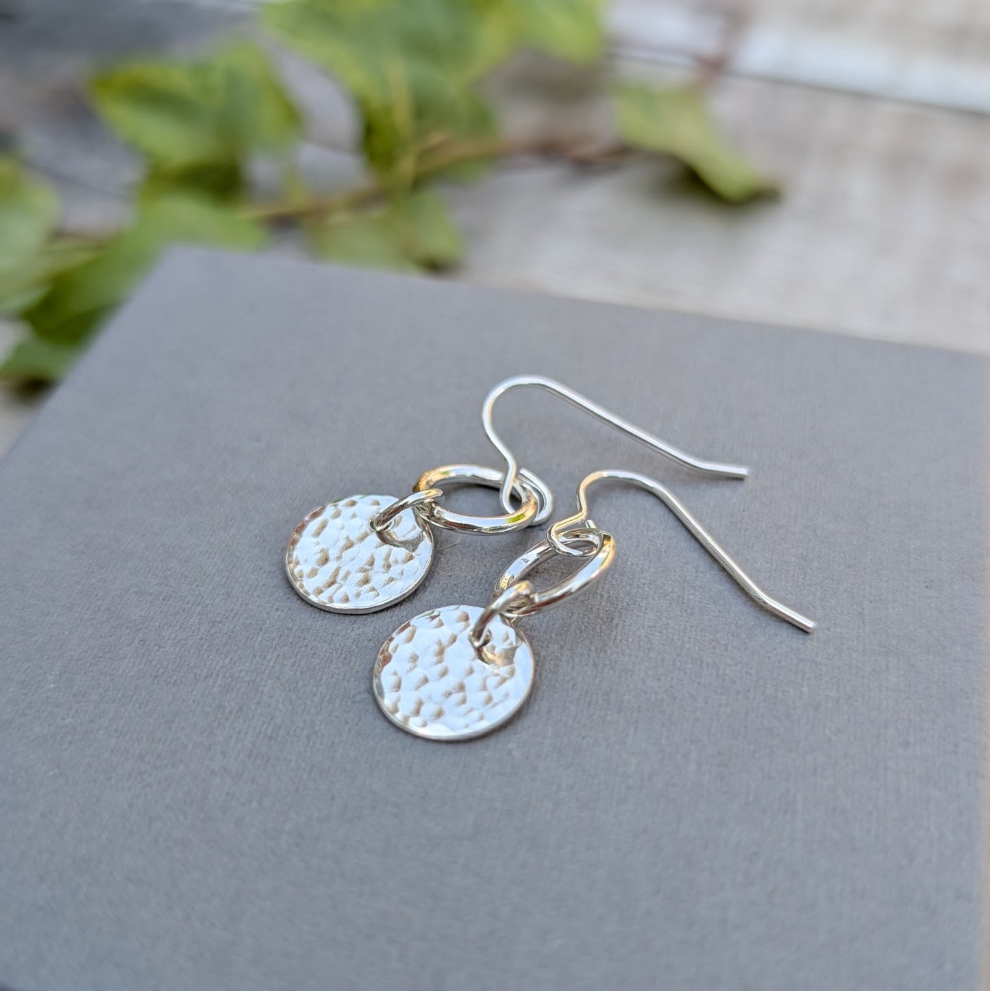 Close-up of Silver hammered disc and circle earrings handmade from recycled Sterling Silver with polished circle links and hammered disc charms.