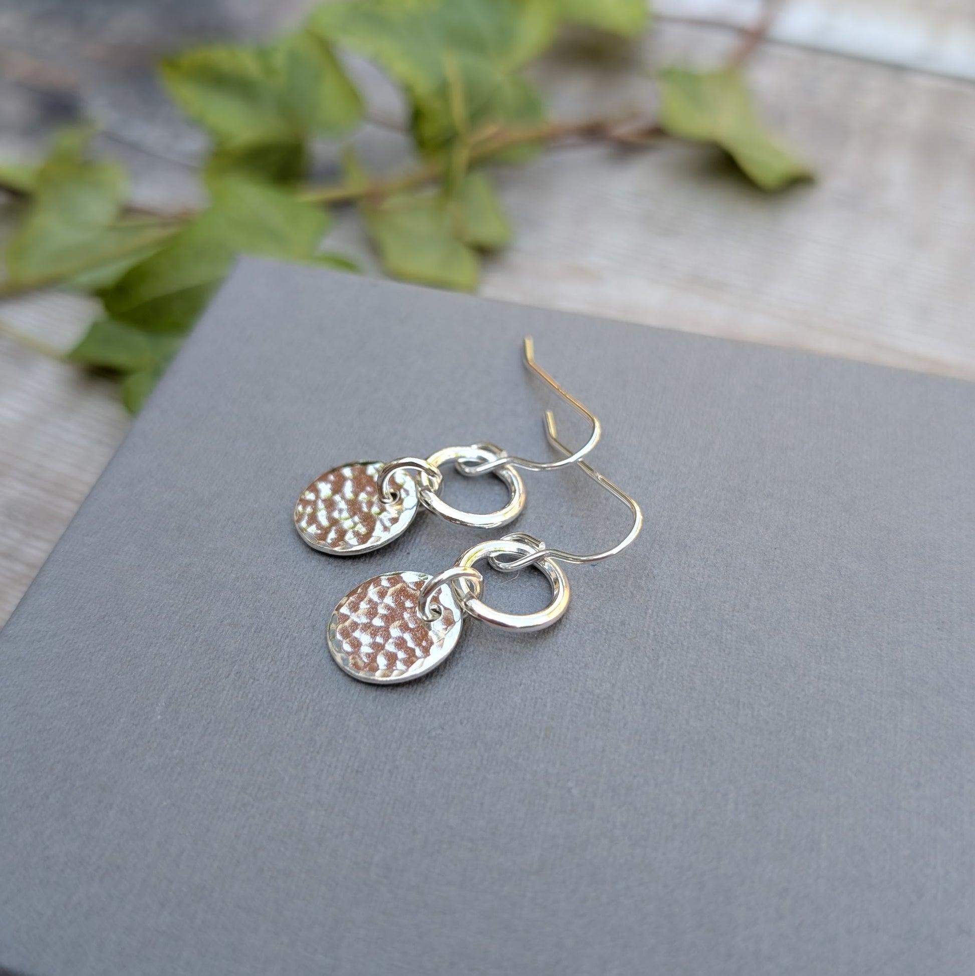 Silver hammered disc and circle earrings handmade from recycled Sterling Silver photographed on a grey card, showing the hammered texture and polished finish.