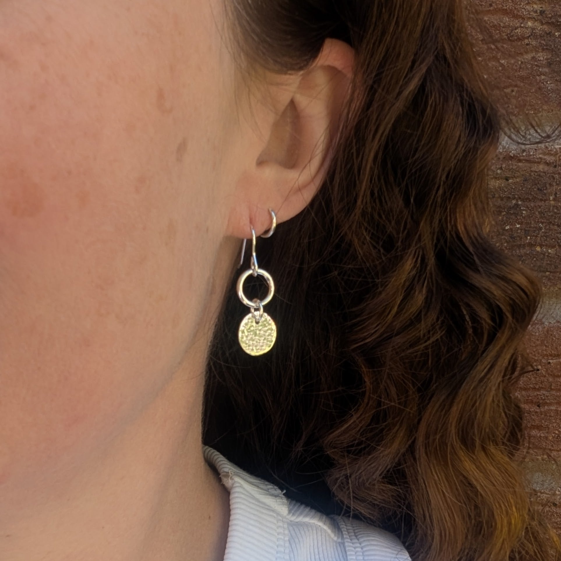 Handmade Silver hammered disc and circle earrings in recycled Sterling Silver worn on the ear, showing their lightweight drop style.