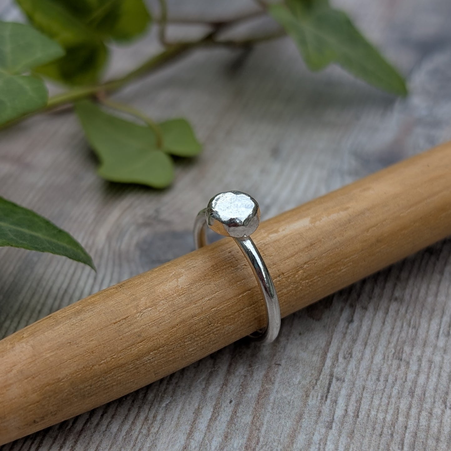 Silver Hammered Pebble Ring on a wooden mandrel, focusing on the smooth band and hammered pebble surface