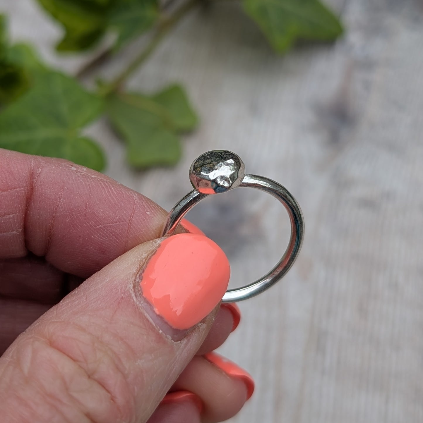 Close-up of Silver Hammered Pebble Ring held between fingers, highlighting the hammered texture