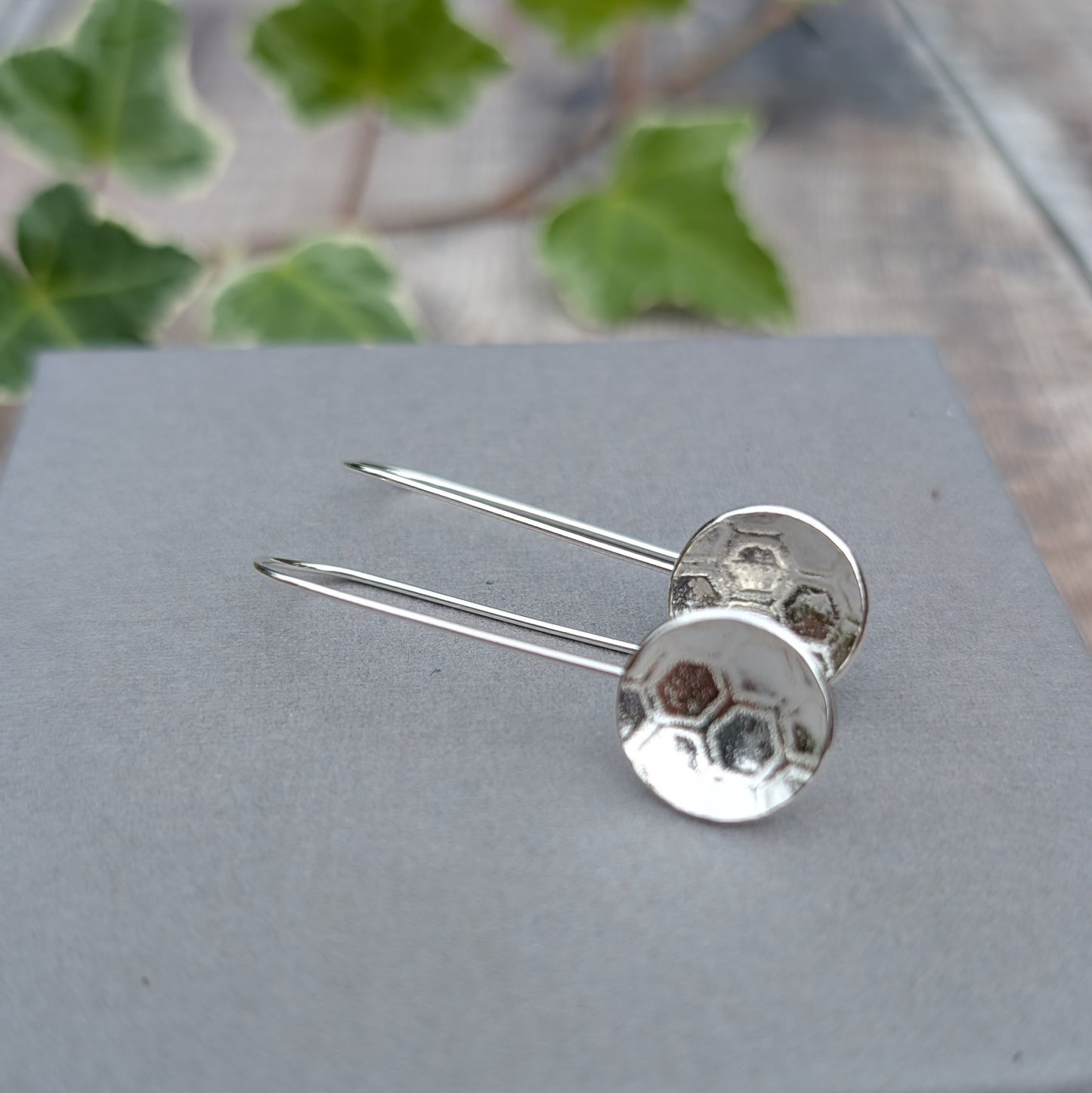Close up of silver honeycomb long disc earrings showing the textured round silver discs and long handmade ear wires.