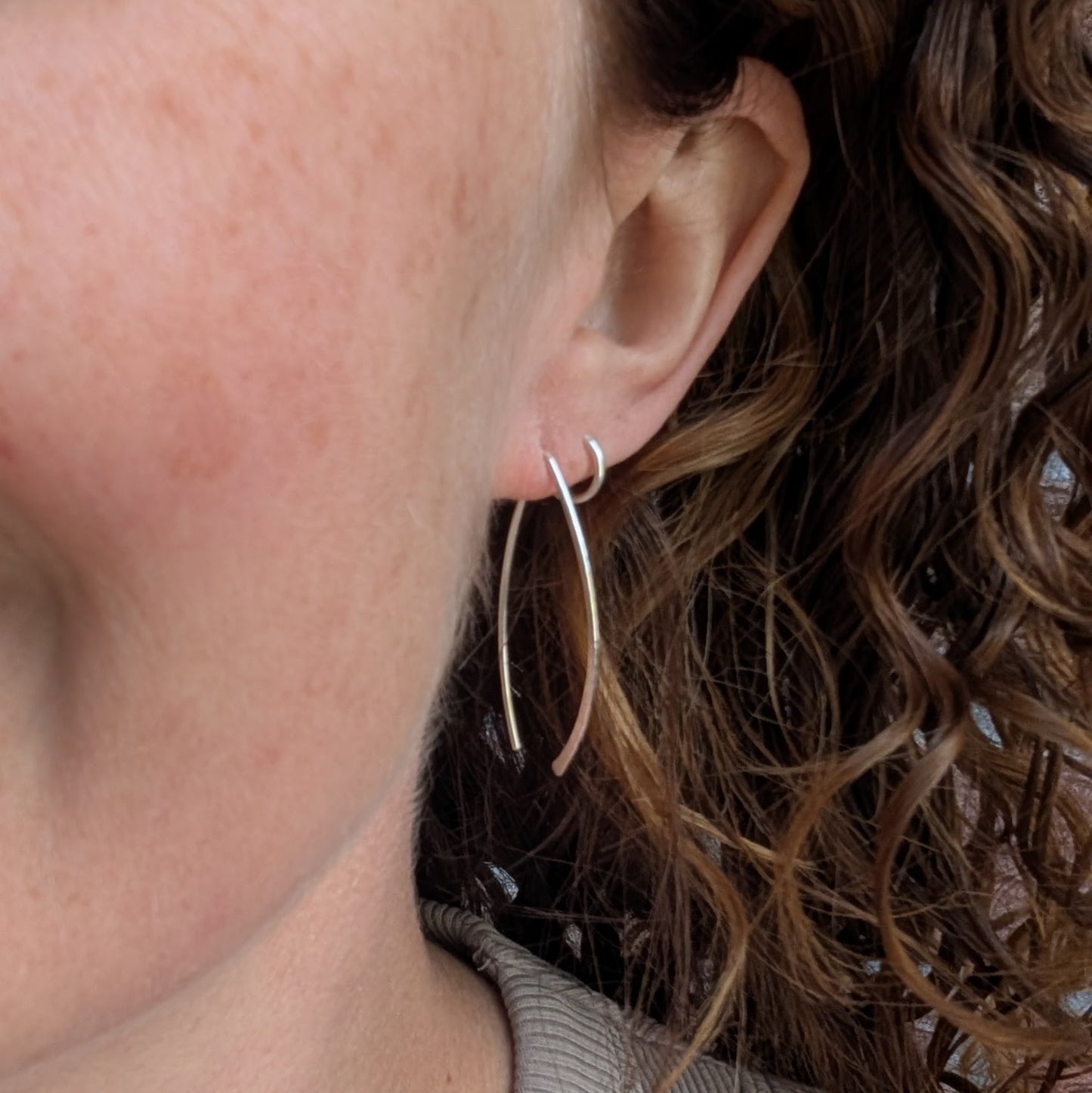 Silver Large Threader Earrings handmade from recycled sterling silver being worn in the ear, showing their long curved threader shape.