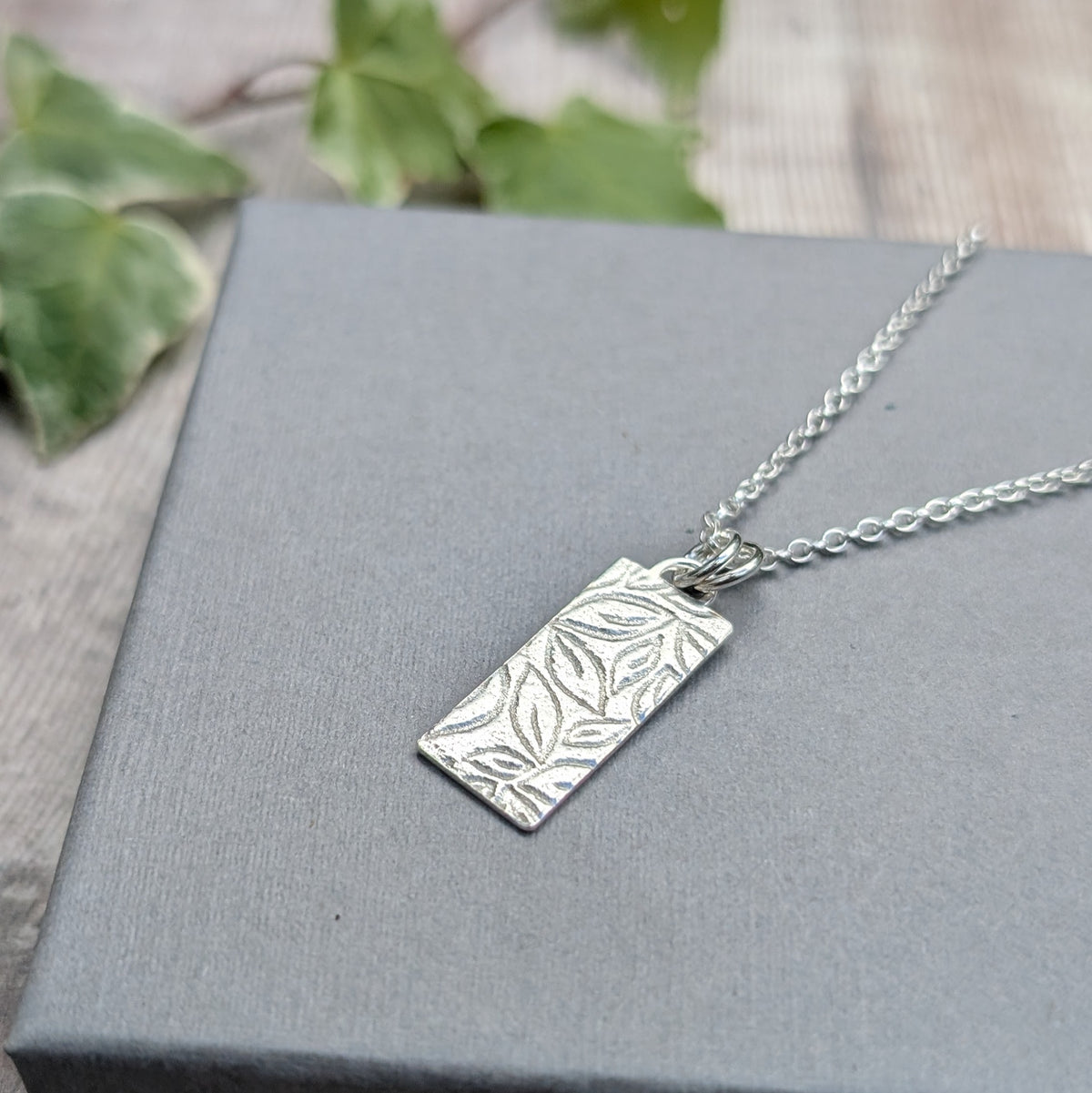 Close up of a silver leaves rectangle necklace handmade from recycled Sterling Silver, showing the detailed leaf pattern applied using a rolling mill.