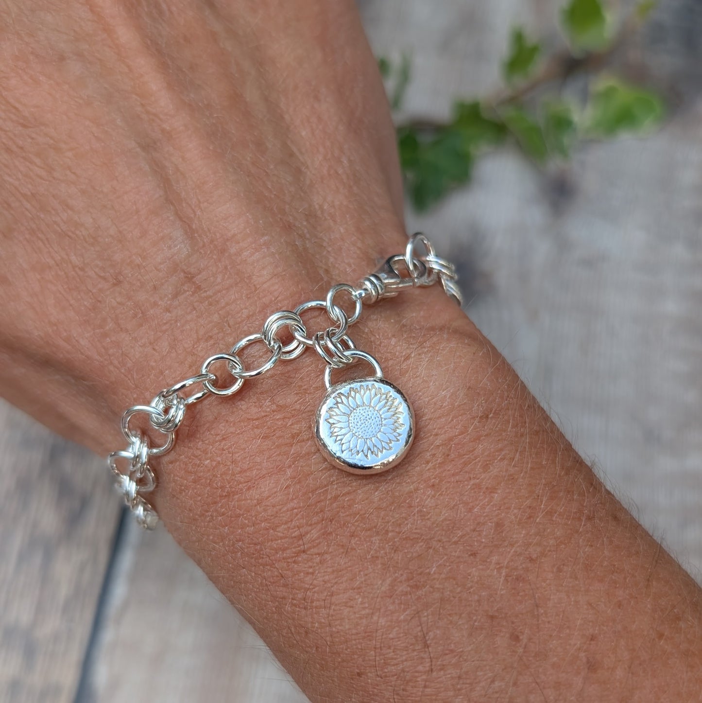 Silver Chain Link Bracelet with Sunflower Charm worn on the wrist, showing the recycled Sterling Silver handmade chain and sunflower pebble charm.