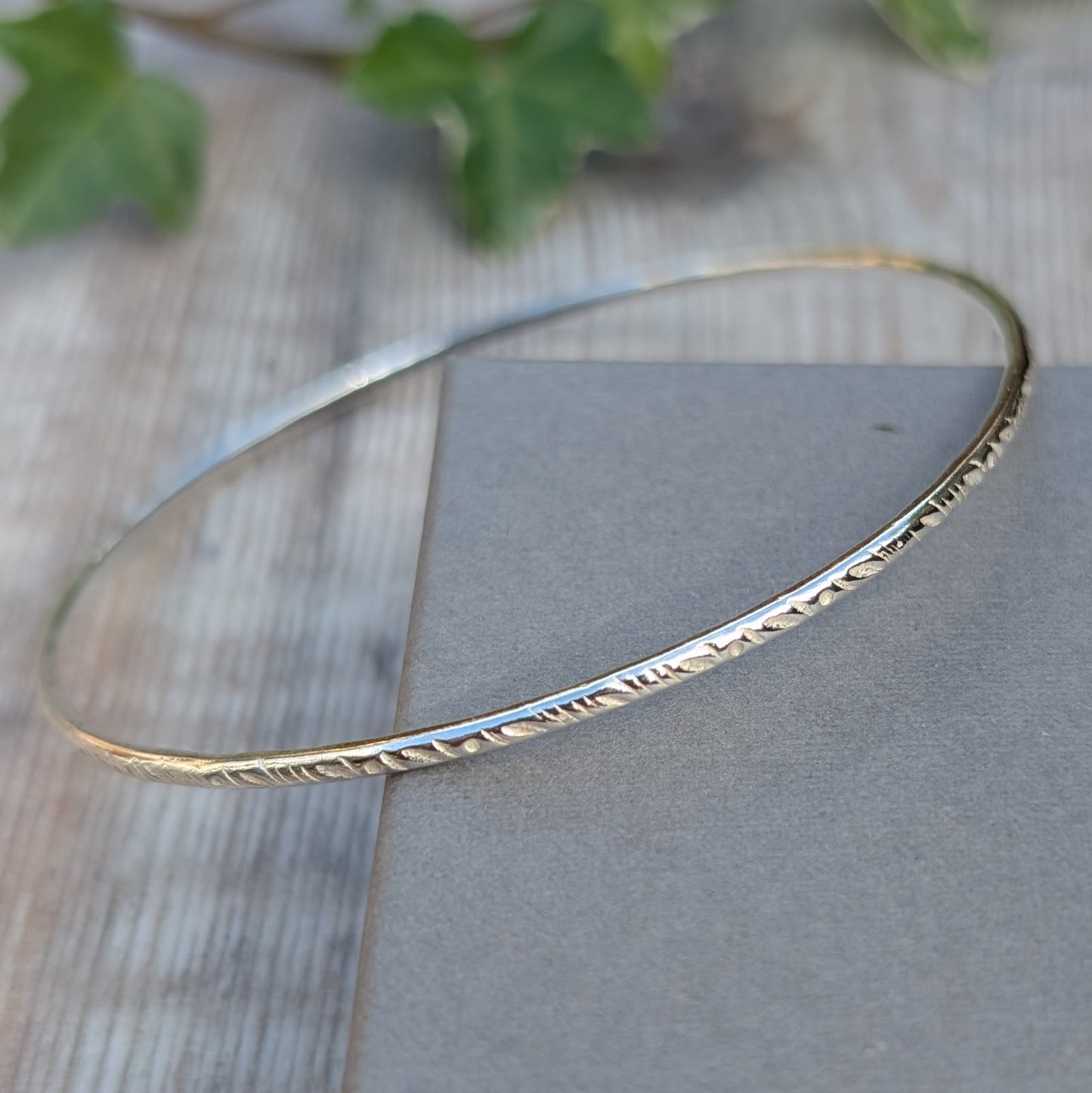 Silver Meadow Patterned 2mm Bangle handmade from recycled Sterling Silver 2mm wire resting on a display block, showing the meadow pattern pressed into the silver using a pattern die.