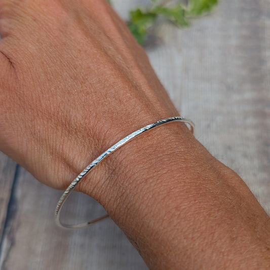 Silver Meadow Patterned 2mm Bangle handmade from recycled Sterling Silver 2mm wire shown being worn on the wrist, featuring a delicate meadow pattern pressed into the silver.