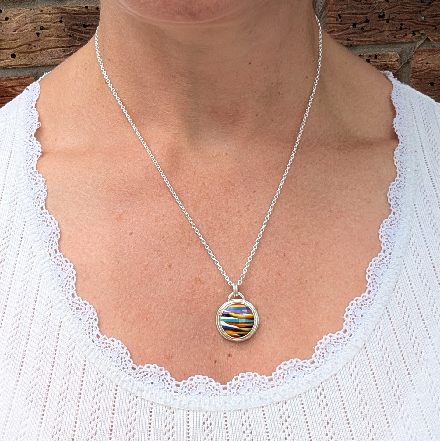 Silver Multicoloured Surfite Round Necklace being worn, showing the size and length of the colourful round Surfite pendant.