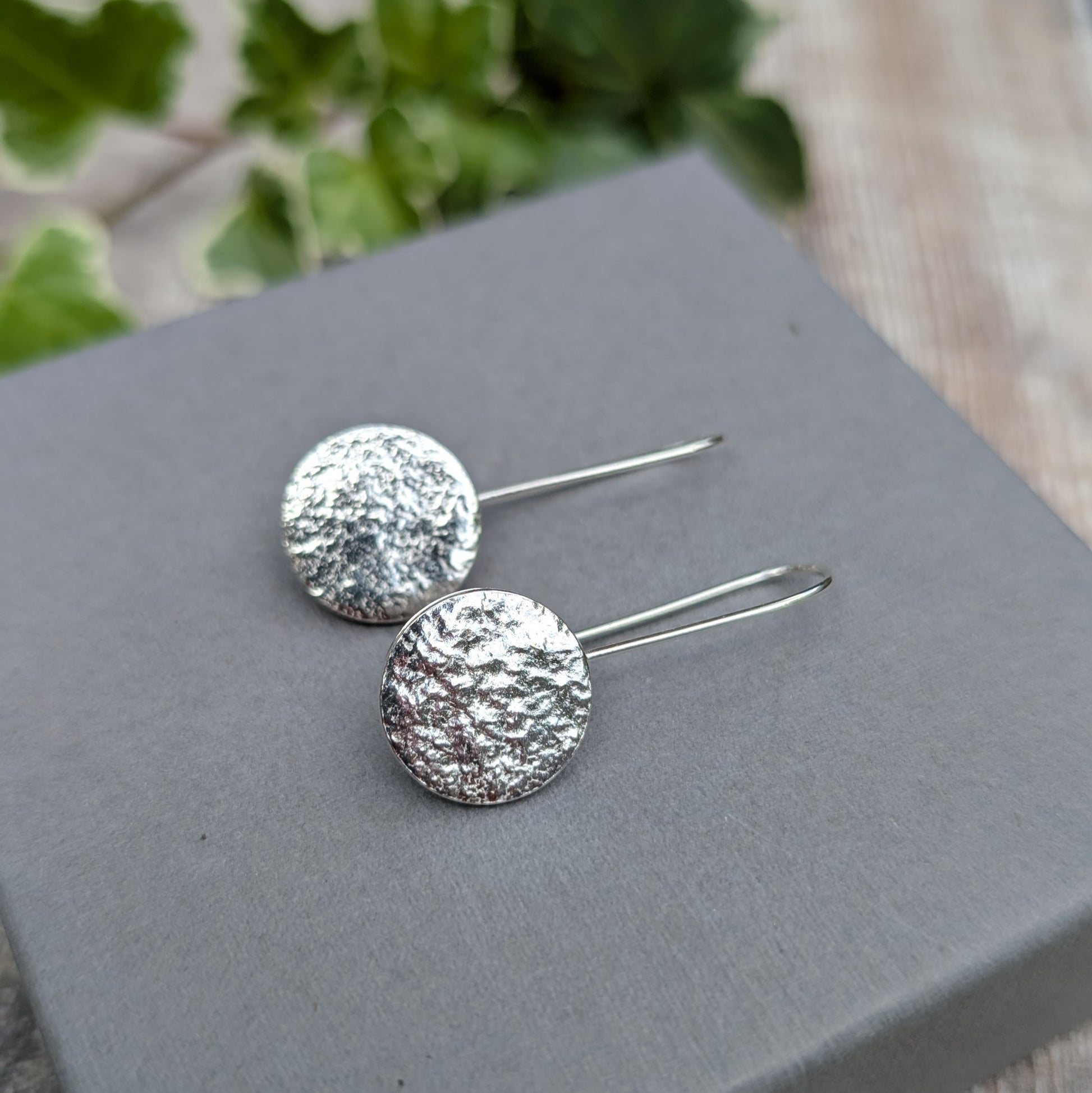 Silver organic disc long earrings handmade from recycled Sterling Silver, with textured round discs and long ear wires, displayed on a grey box.