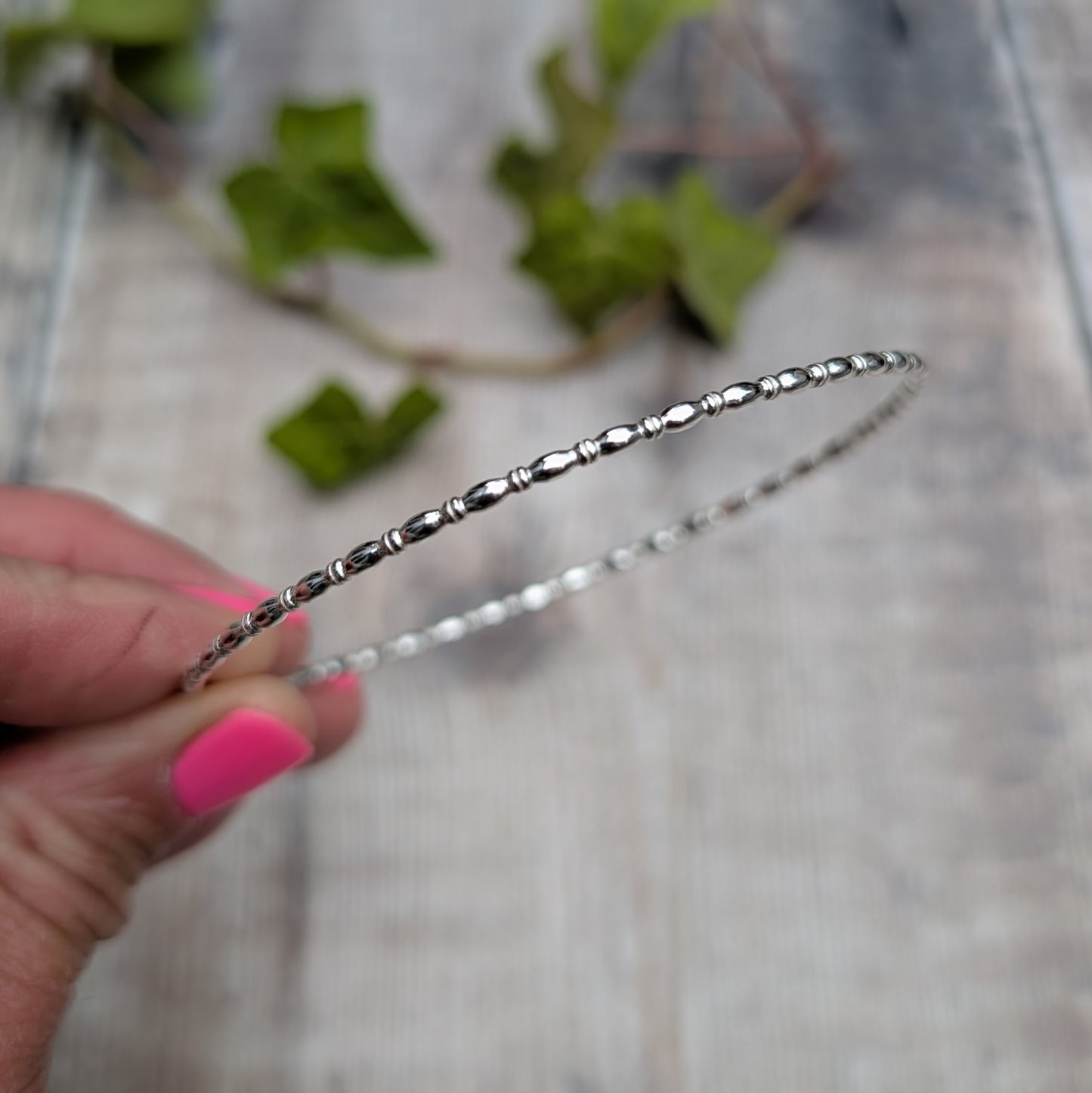 Close up of the Silver Oval Beaded Wire Round Bangle handmade from recycled Sterling Silver 2mm square wire, showing the oval beaded detail.