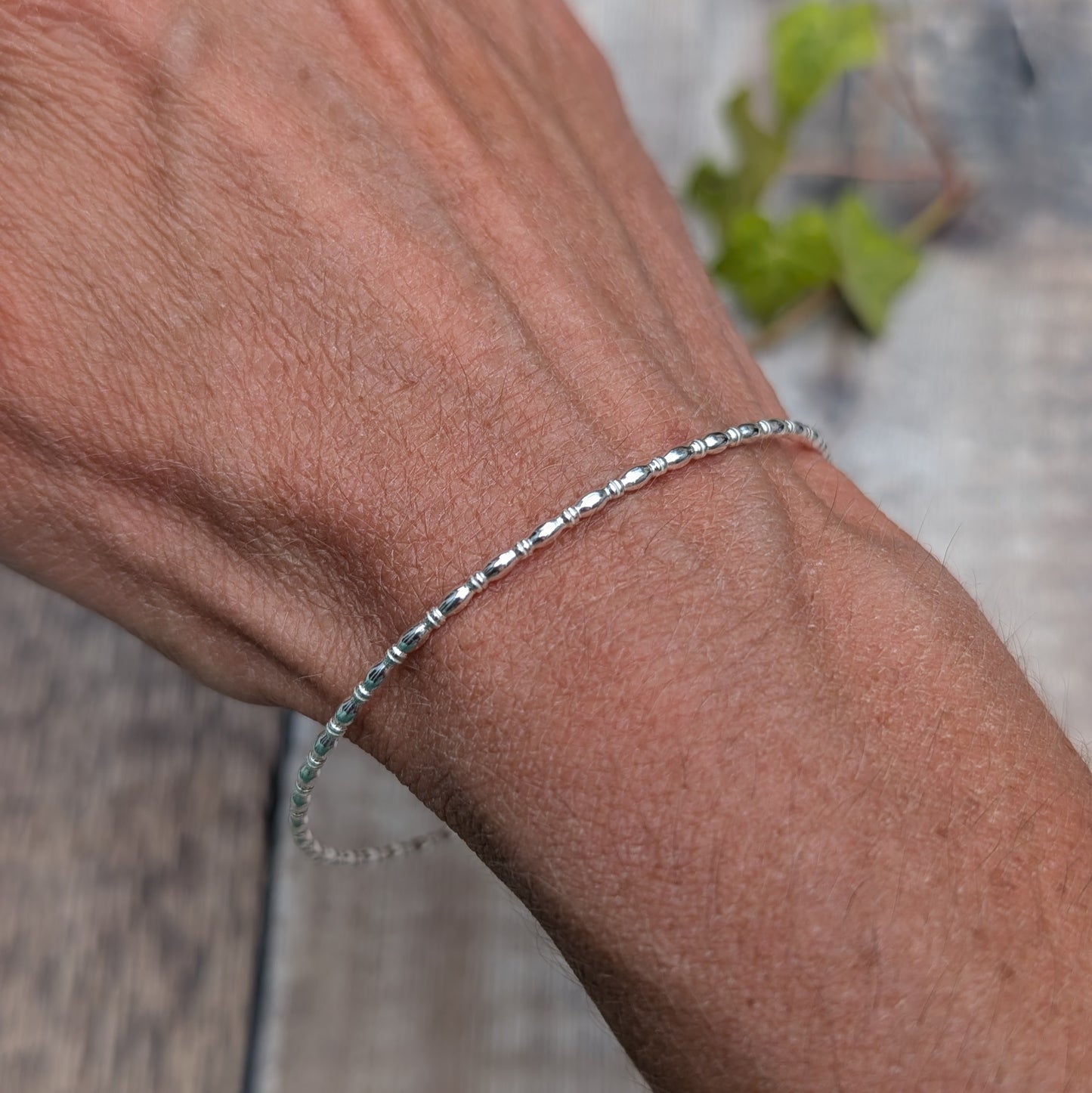 Silver Oval Beaded Wire Round Bangle handmade from recycled Sterling Silver 2mm square wire, worn on the wrist to show the fit and delicate design.