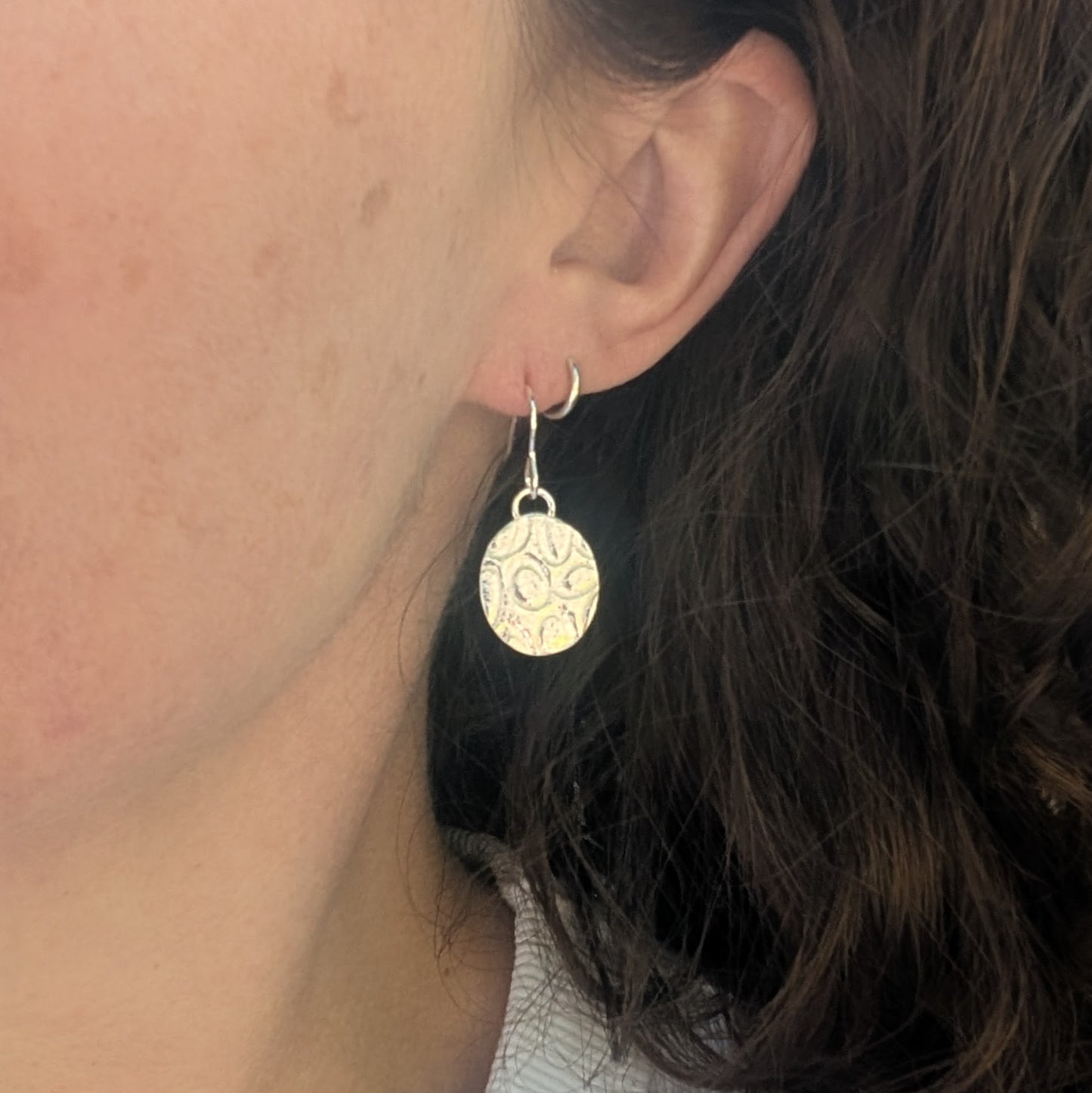 Silver Oval Disc Earrings with Oval Pattern worn on ear showing how they hang