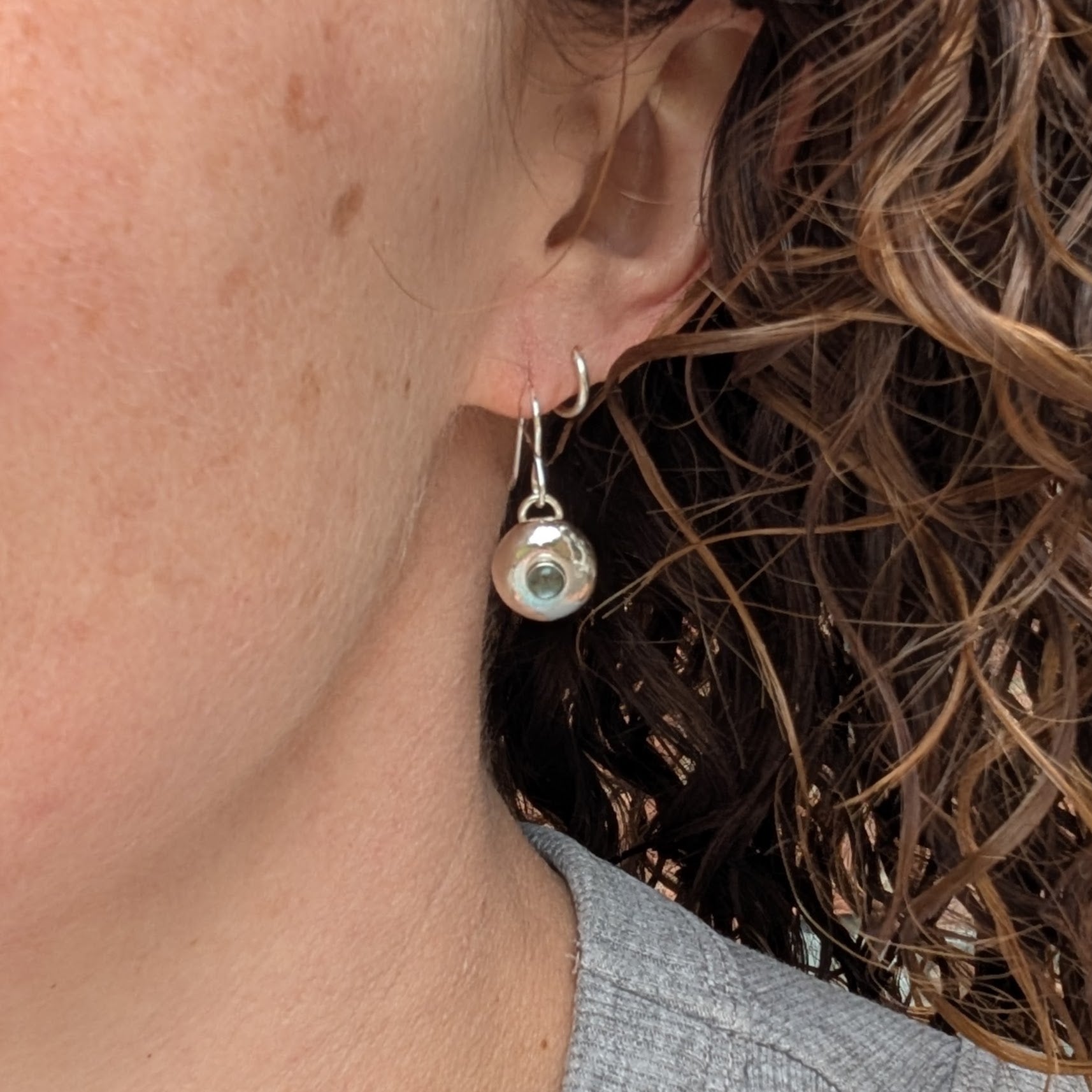 Silver Pebble Earrings with Blue Topaz worn on ear showing size and drop length