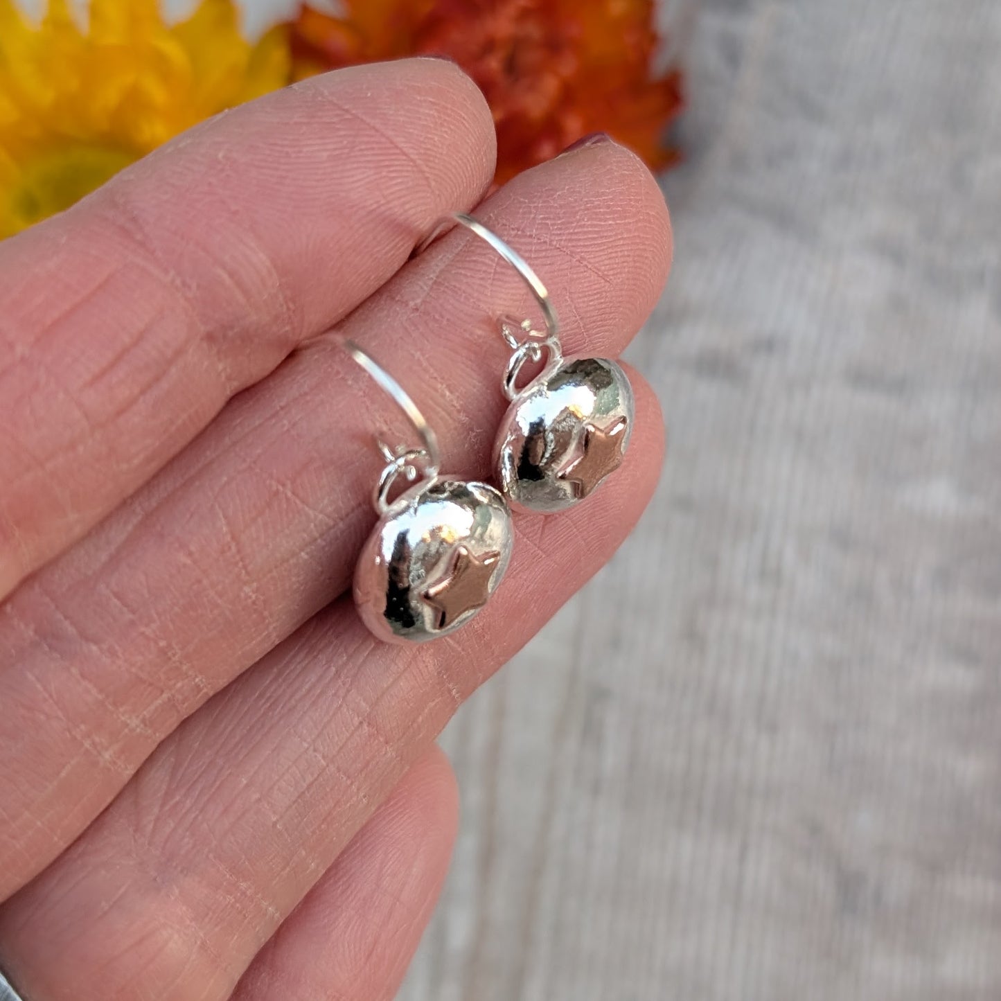 Silver and copper star pebble earrings on handmade ear wires, shown from the side.
