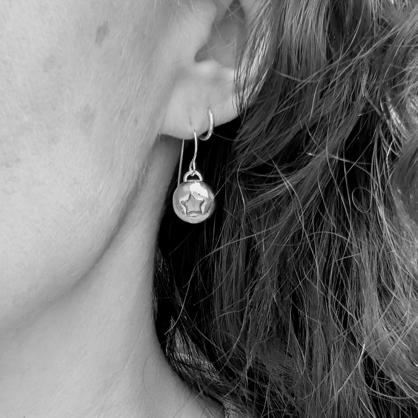 Silver pebble earrings with copper stars, shown worn to demonstrate drop length.