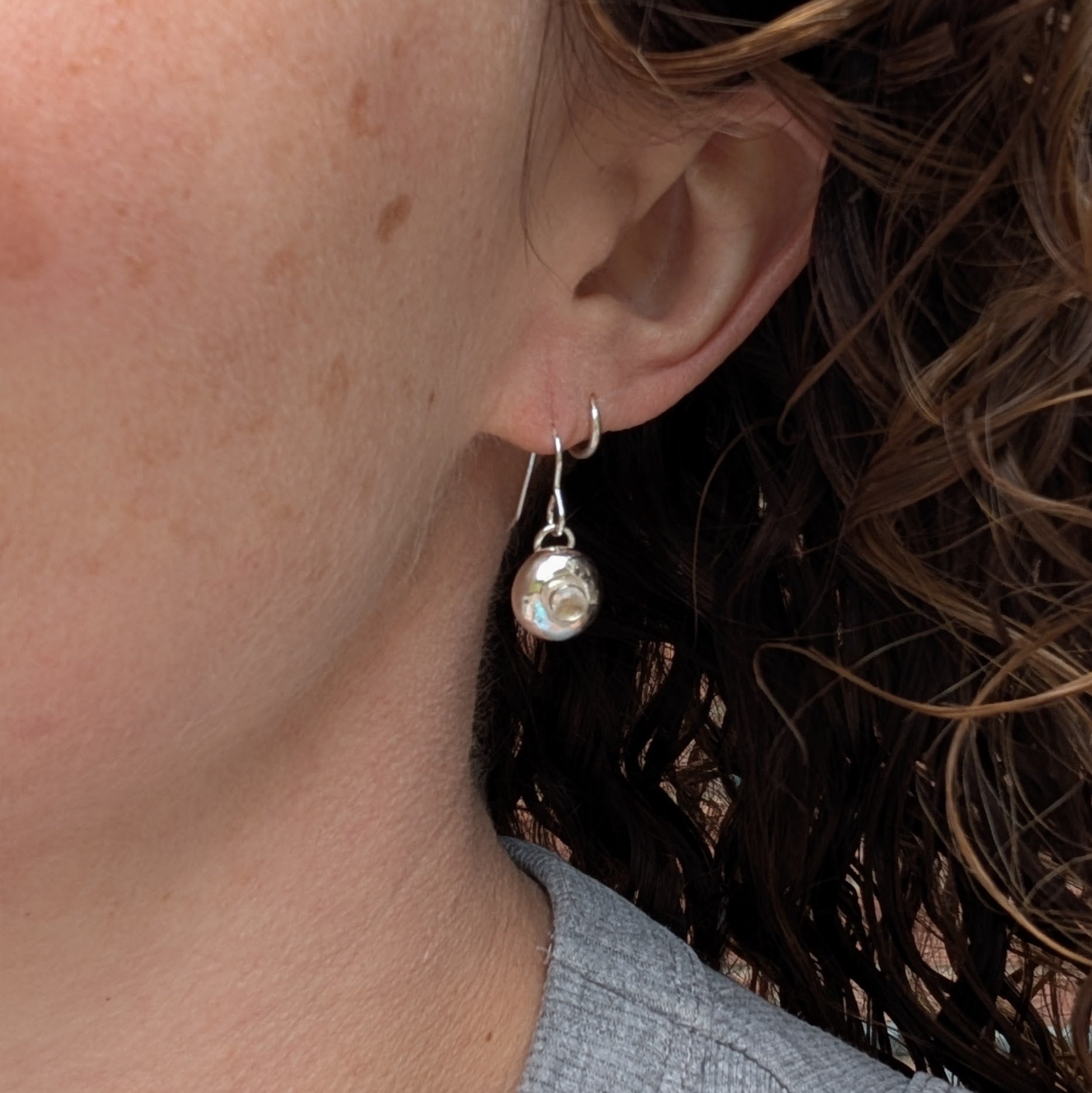 Silver Pebble Earrings with Crystal Quartz worn on an ear