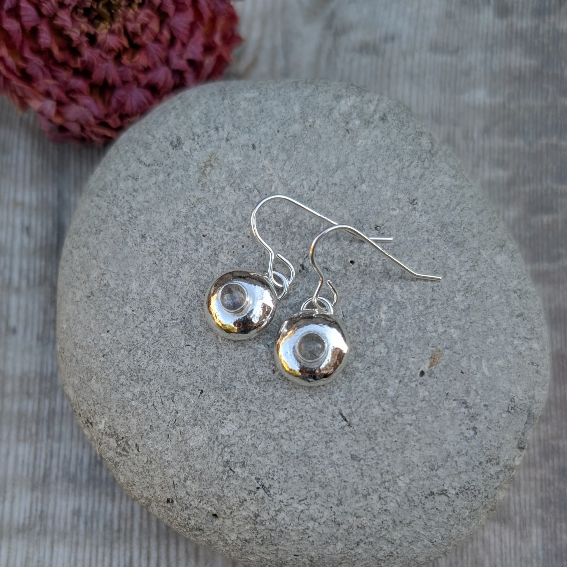 Pair of silver pebble earrings with Labradorite displayed on a smooth grey stone.