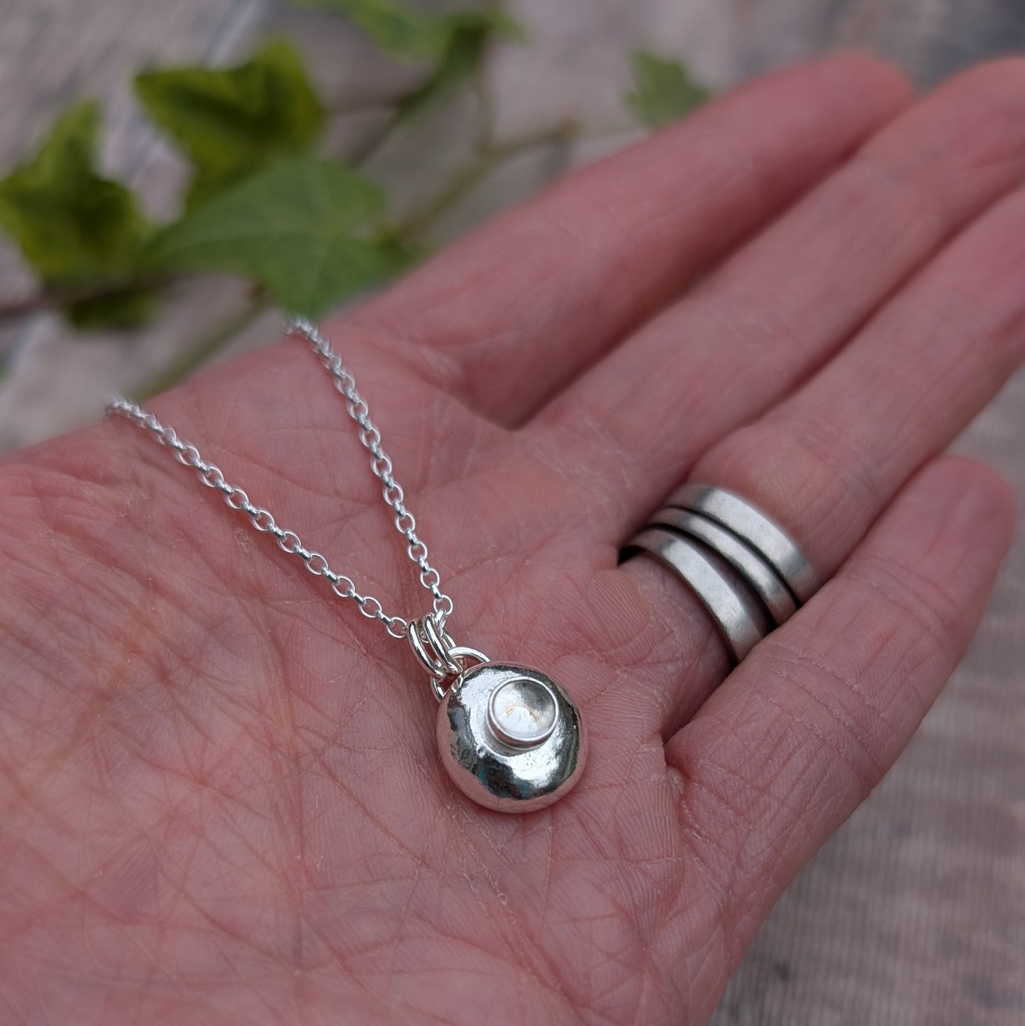 Silver Pebble Necklace with Crystal Quartz in hand with soft natural background