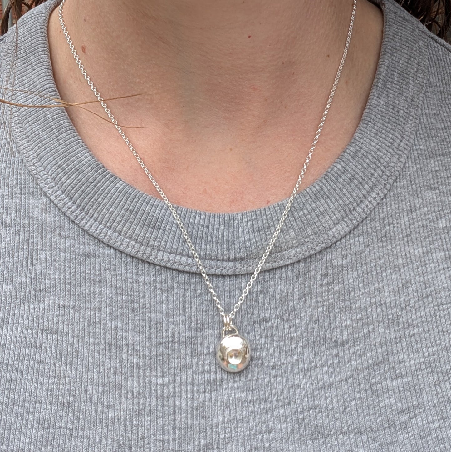 Silver Pebble Necklace with Crystal Quartz worn on a neck with a simple grey top