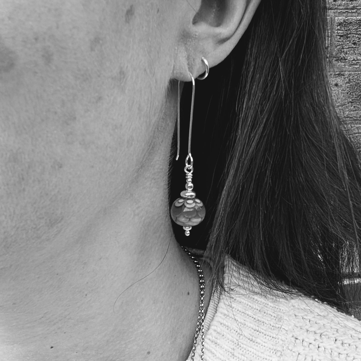 Silver petals lampwork glass bead earrings worn in the ear, showing the length of the silver ear wires and how the glass bead drops sit when worn.