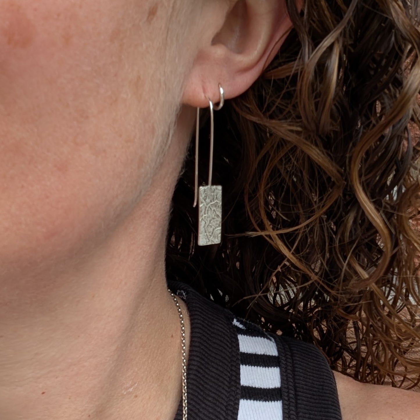 Silver Rectangle Earrings with Cracked Earth Pattern worn on ear showing length and movement